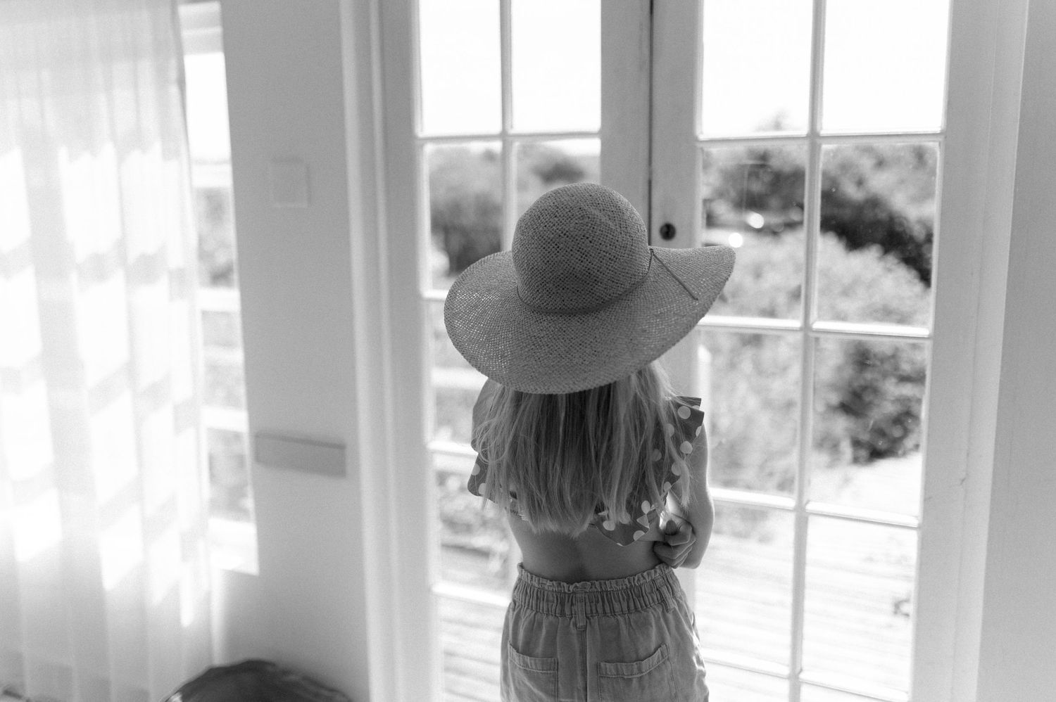 Sun-filled interior room with white walls and large windows overlooking natural scenery.