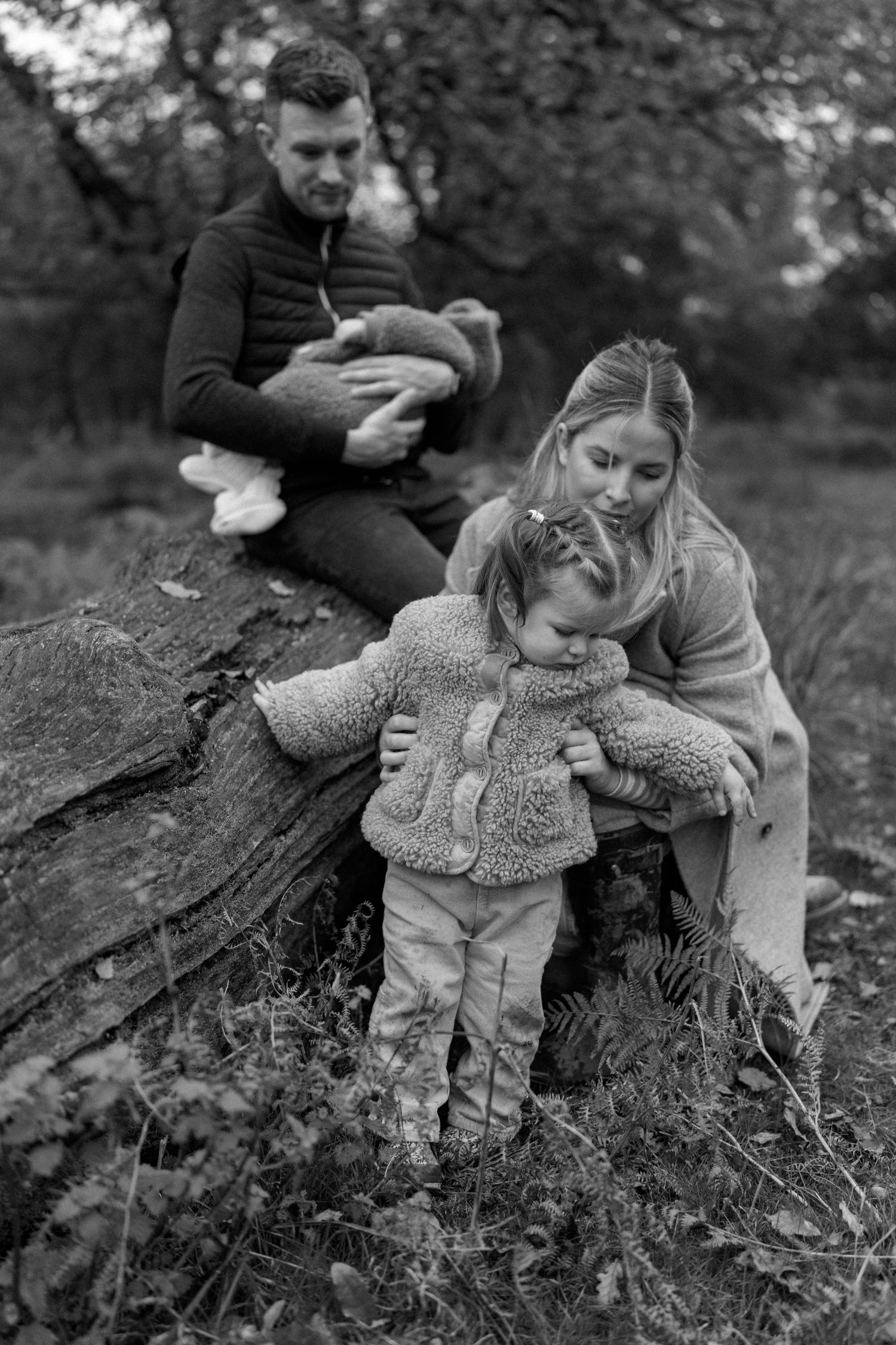 Family enjoying a tender moment together outdoors in black and white photography.