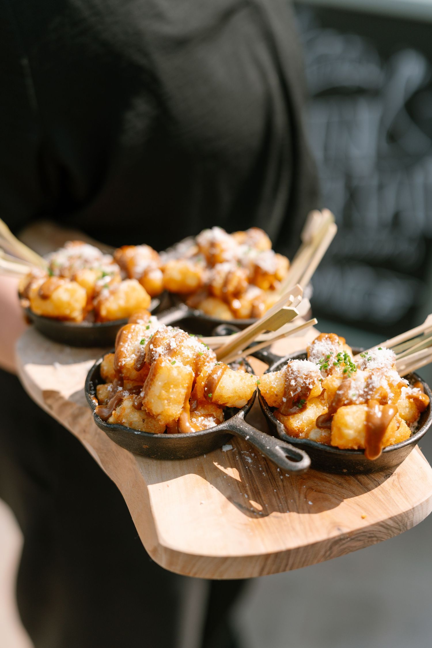 Appetizers served on wooden boards at an outdoor catering event.