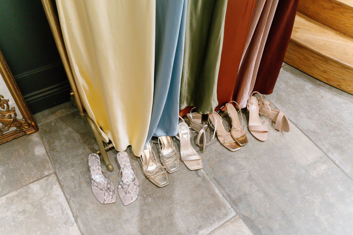 Close-up of formal shoes lined up beneath flowing dresses.