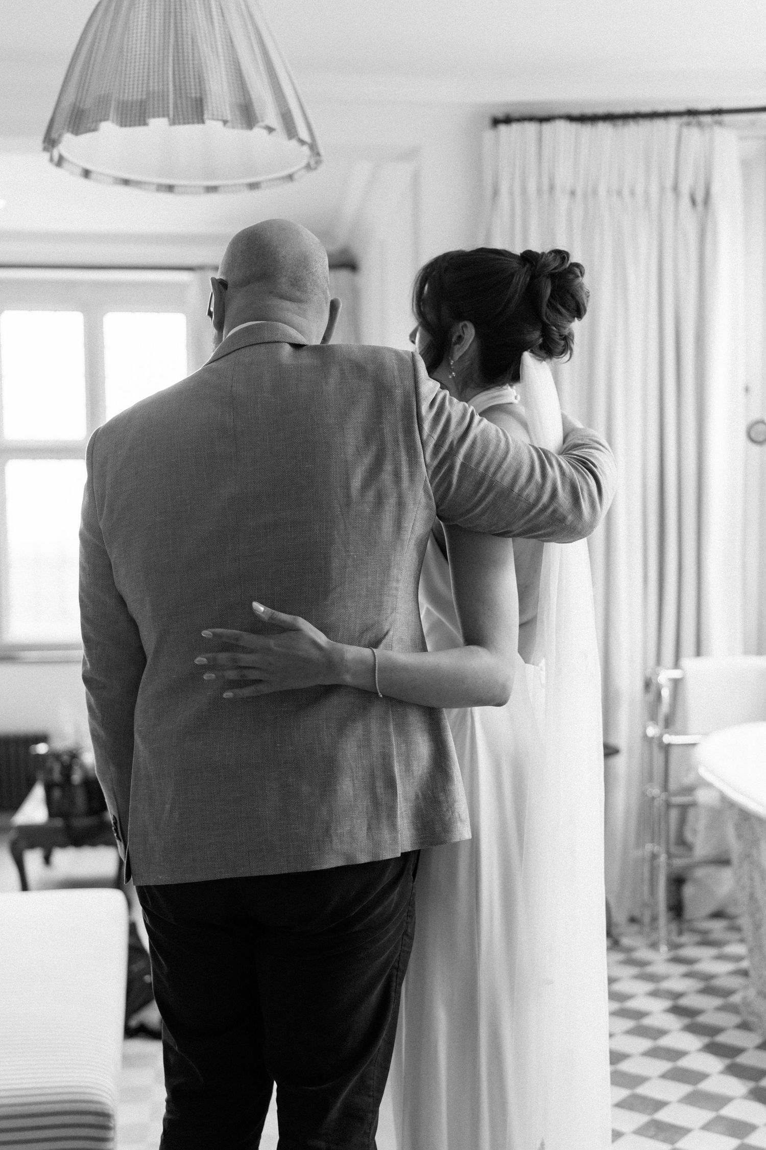 Bride and her father walking arm in arm in a bright elegant room before the ceremony.