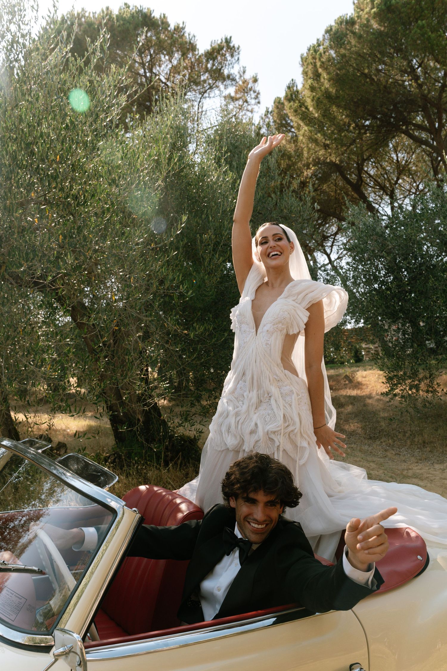 A playful scene in a vintage convertible car with people in white attire enjoying a carefree moment.