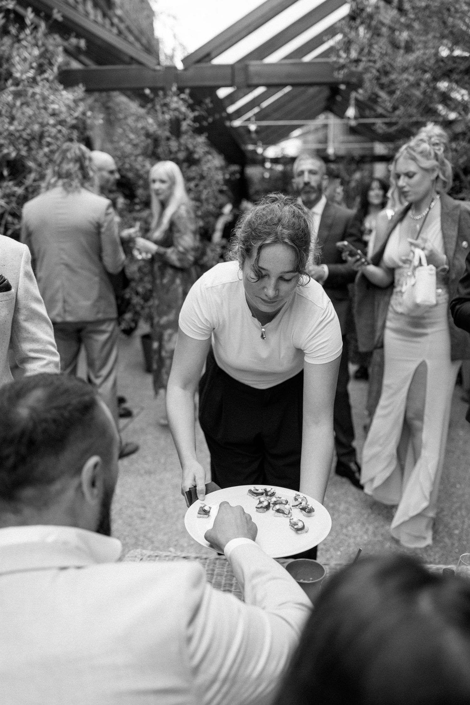 Black and white photo of guests signing a guestbook at wedding reception.