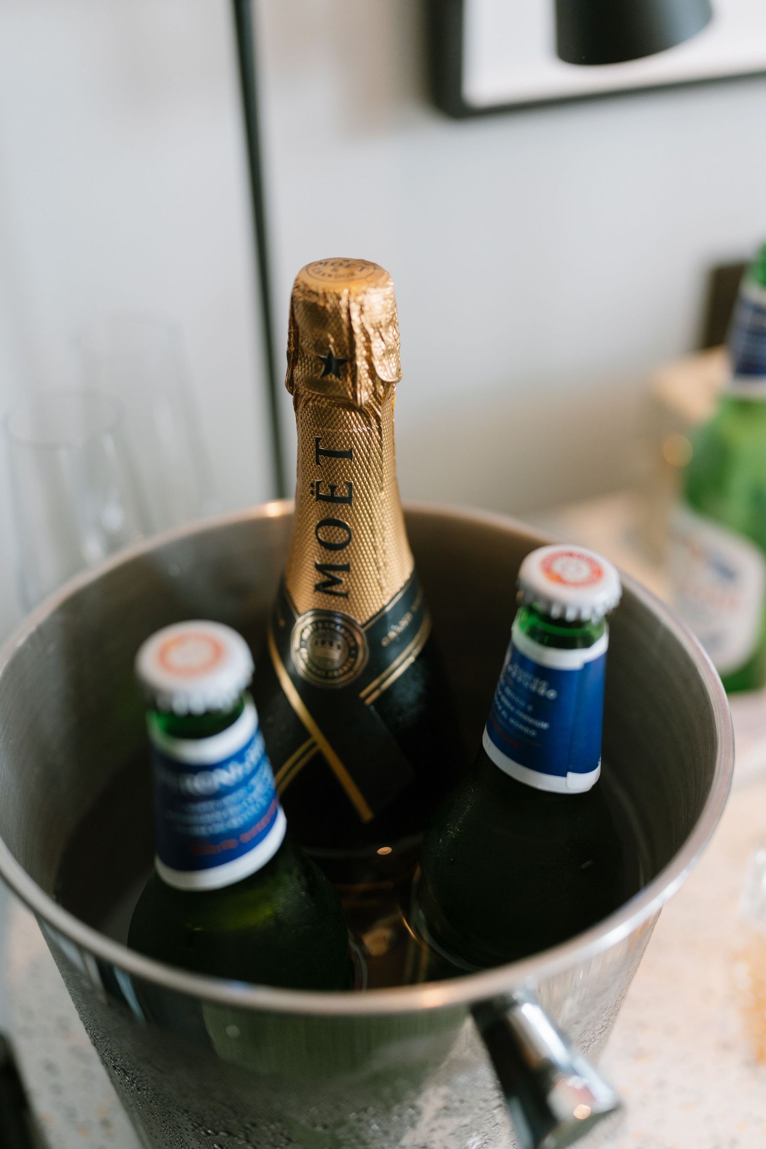 Moet champagne bottle chilling with beer bottles in ice bucket.