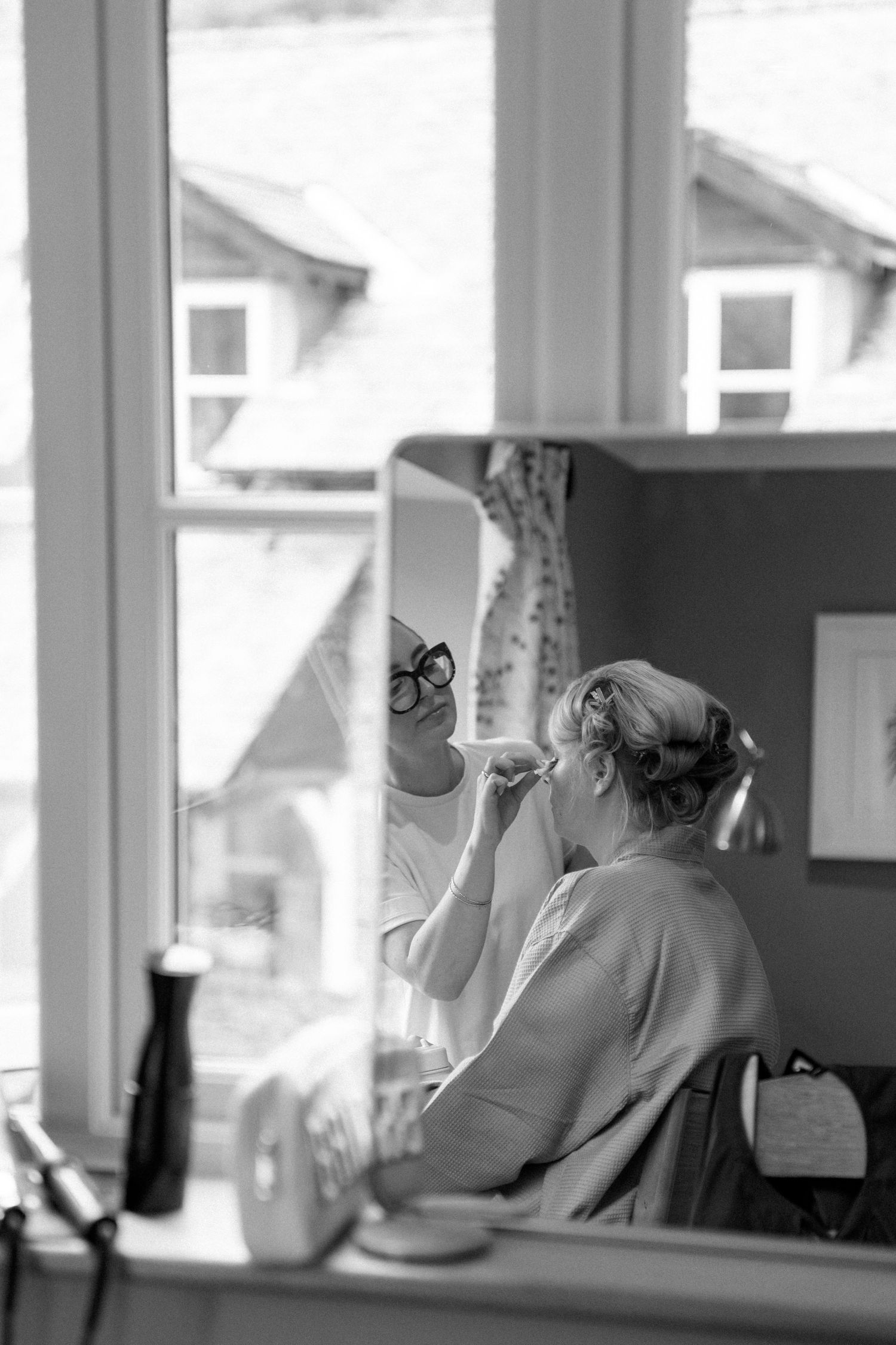 Black and white sequence showing a woman getting ready in front of a window.