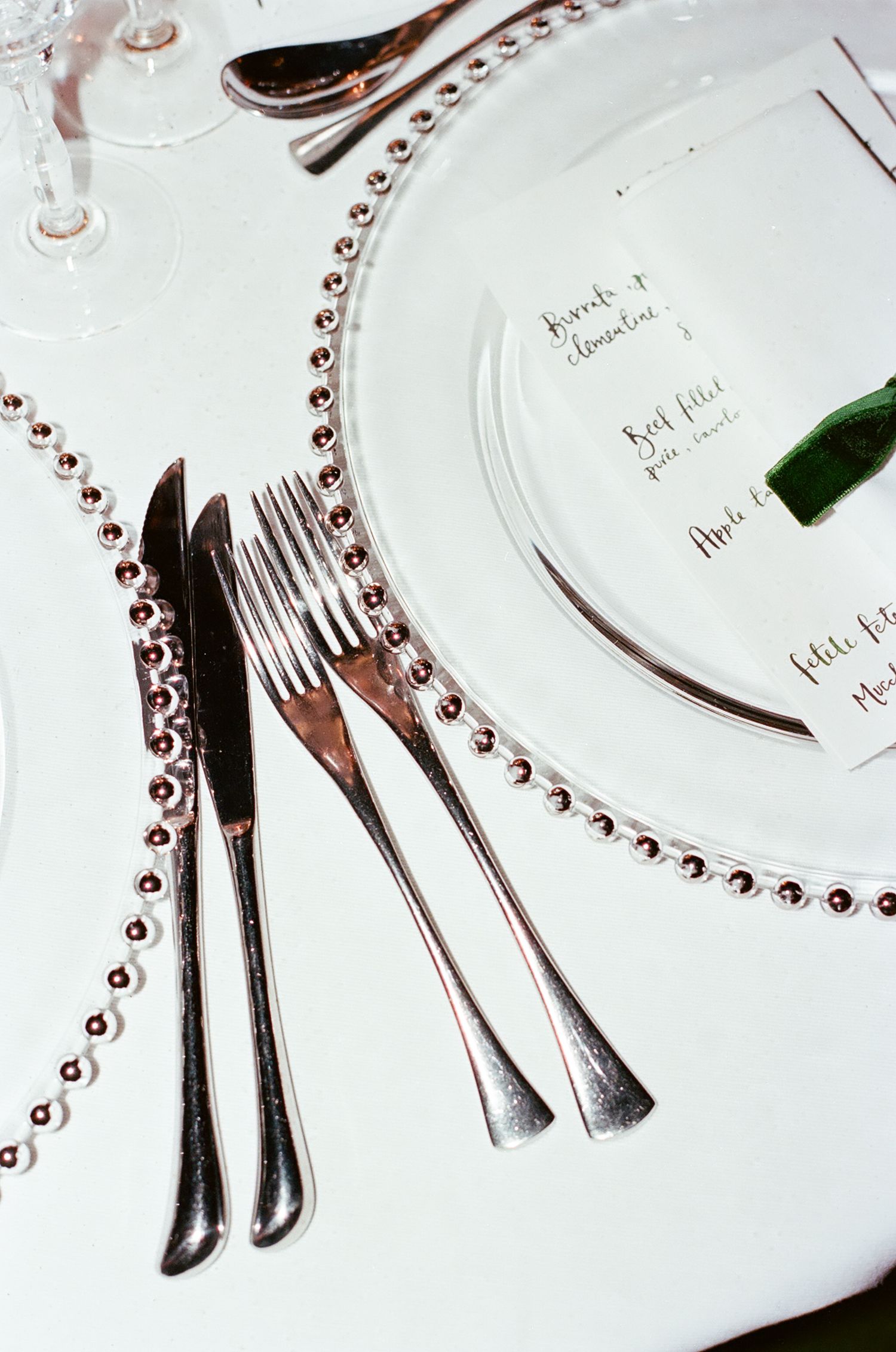 Elegant place settings with white plates and silverware arranged on tables with decorative beaded details.