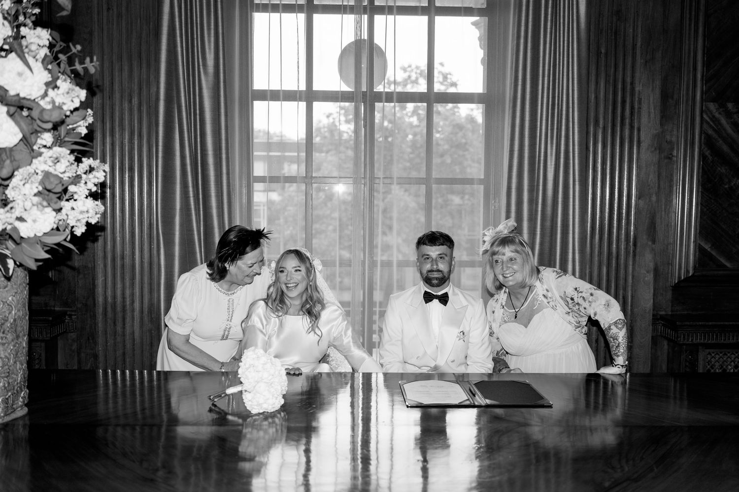 A formal indoor gathering with dark curtains and large windows in an elegant room setting.