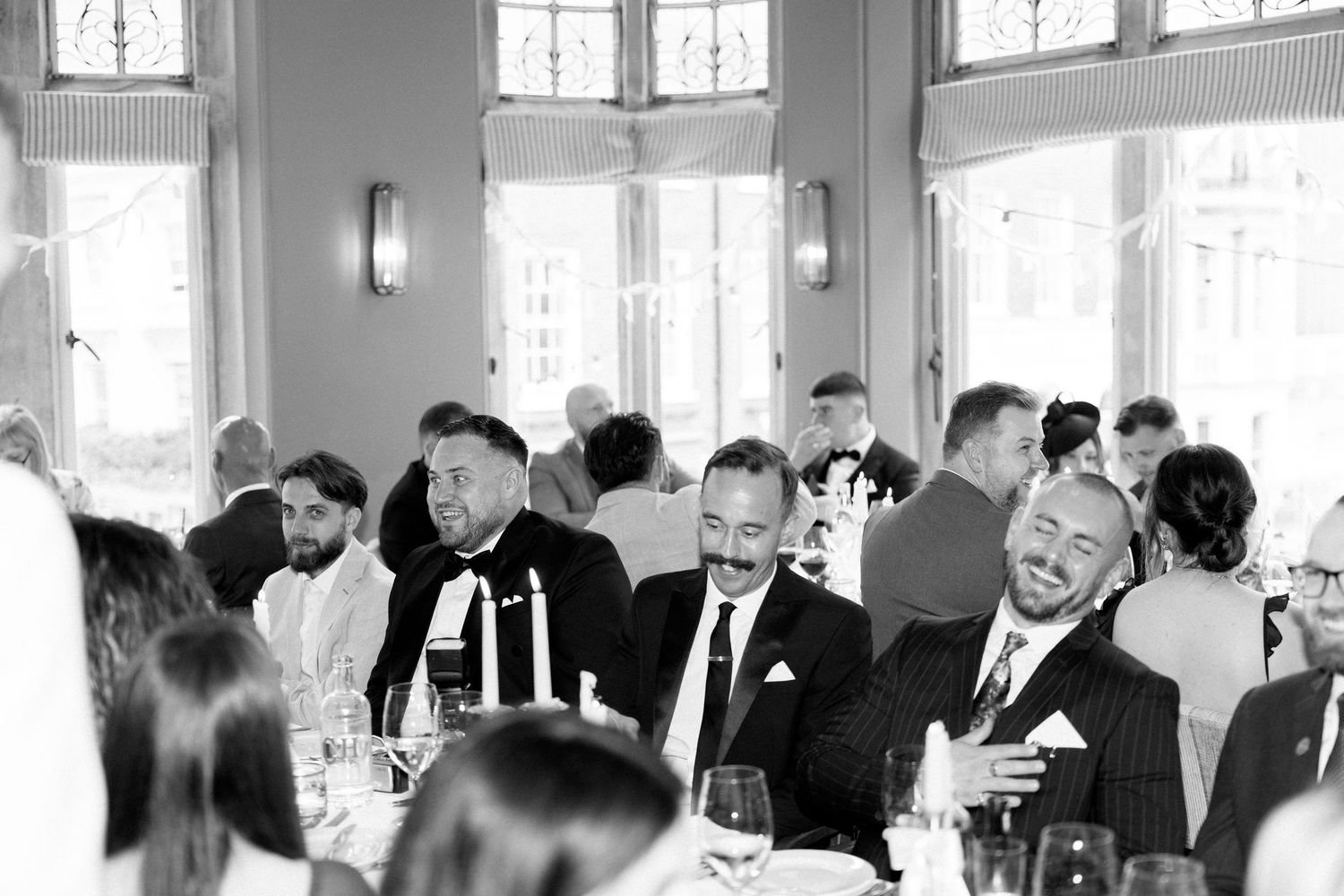 Black and white reception photo of guests enjoying dinner and conversation.