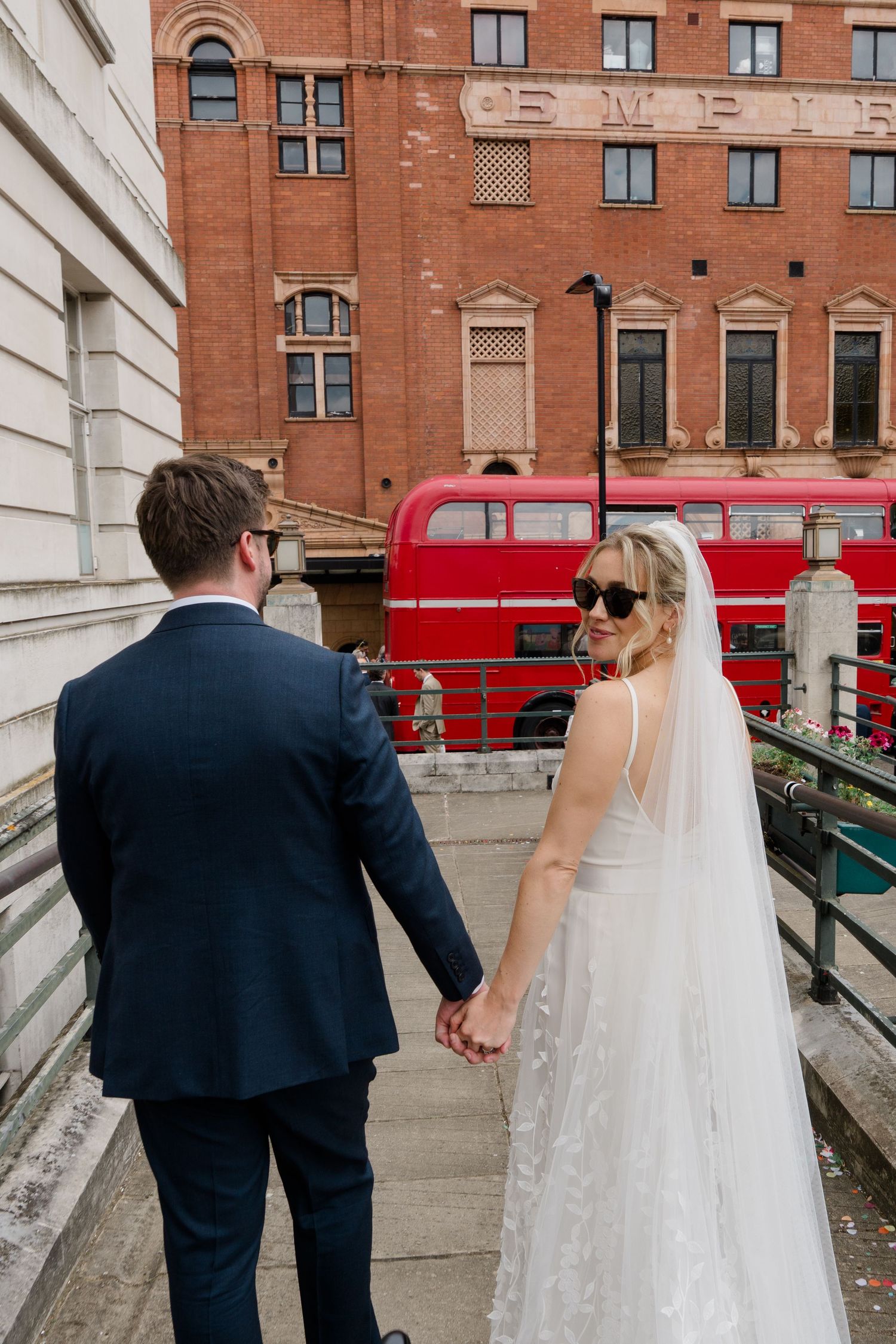 Couple walking up stairs with red double decker bus visible in background.