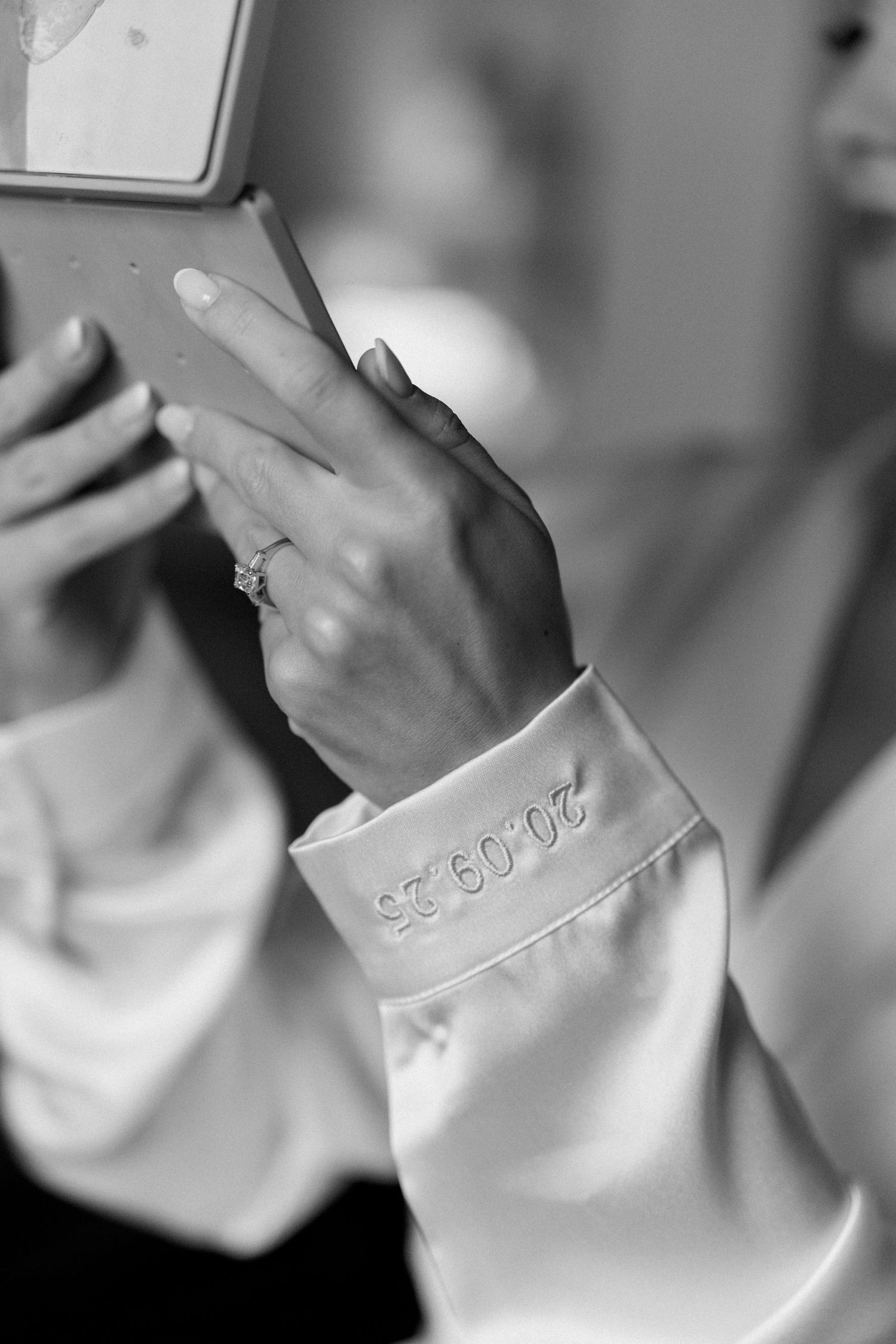 Close-up details of white satin robe sleeve embroidery.