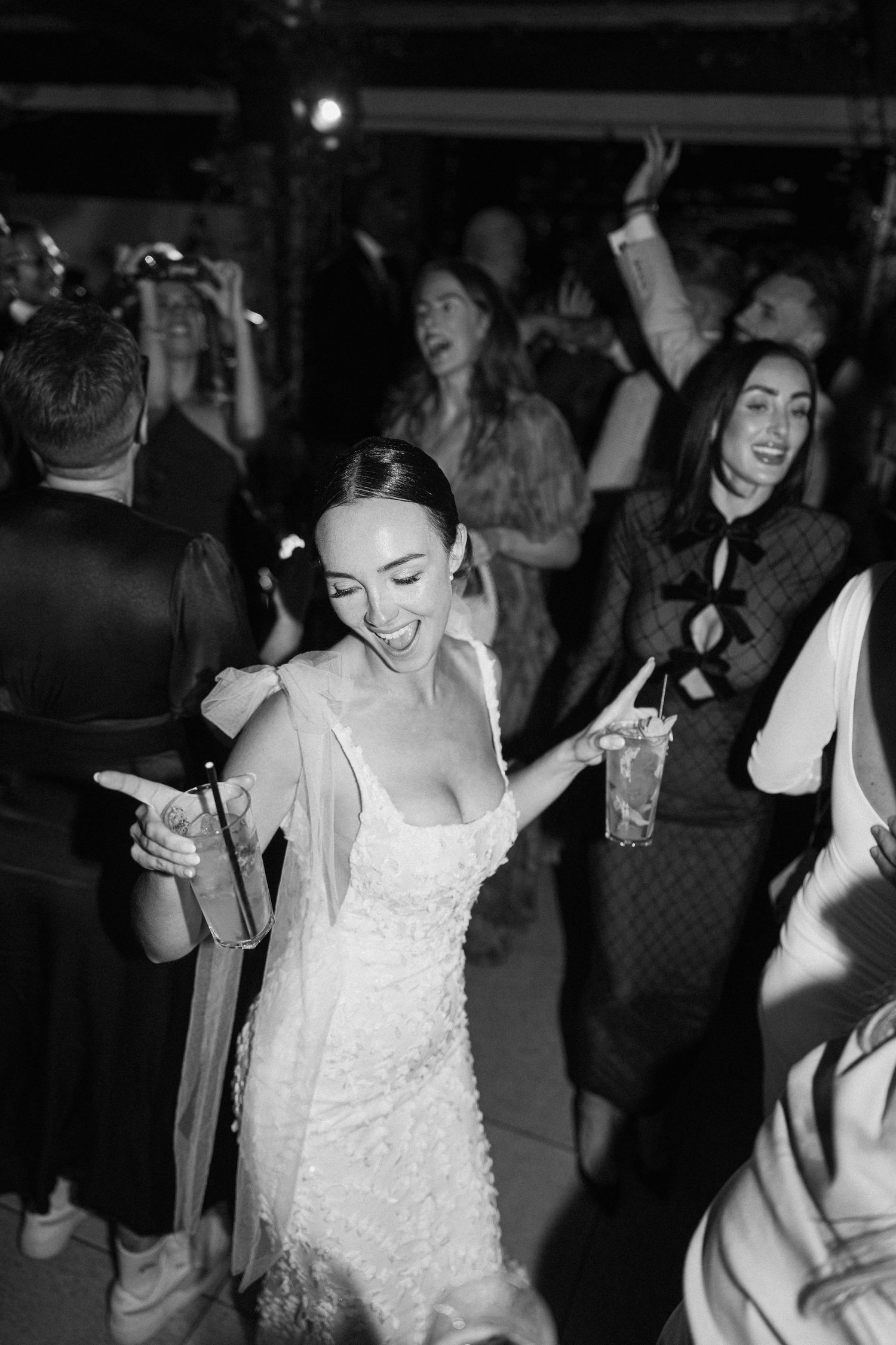 Bride in white lace dress dancing joyfully at wedding reception.