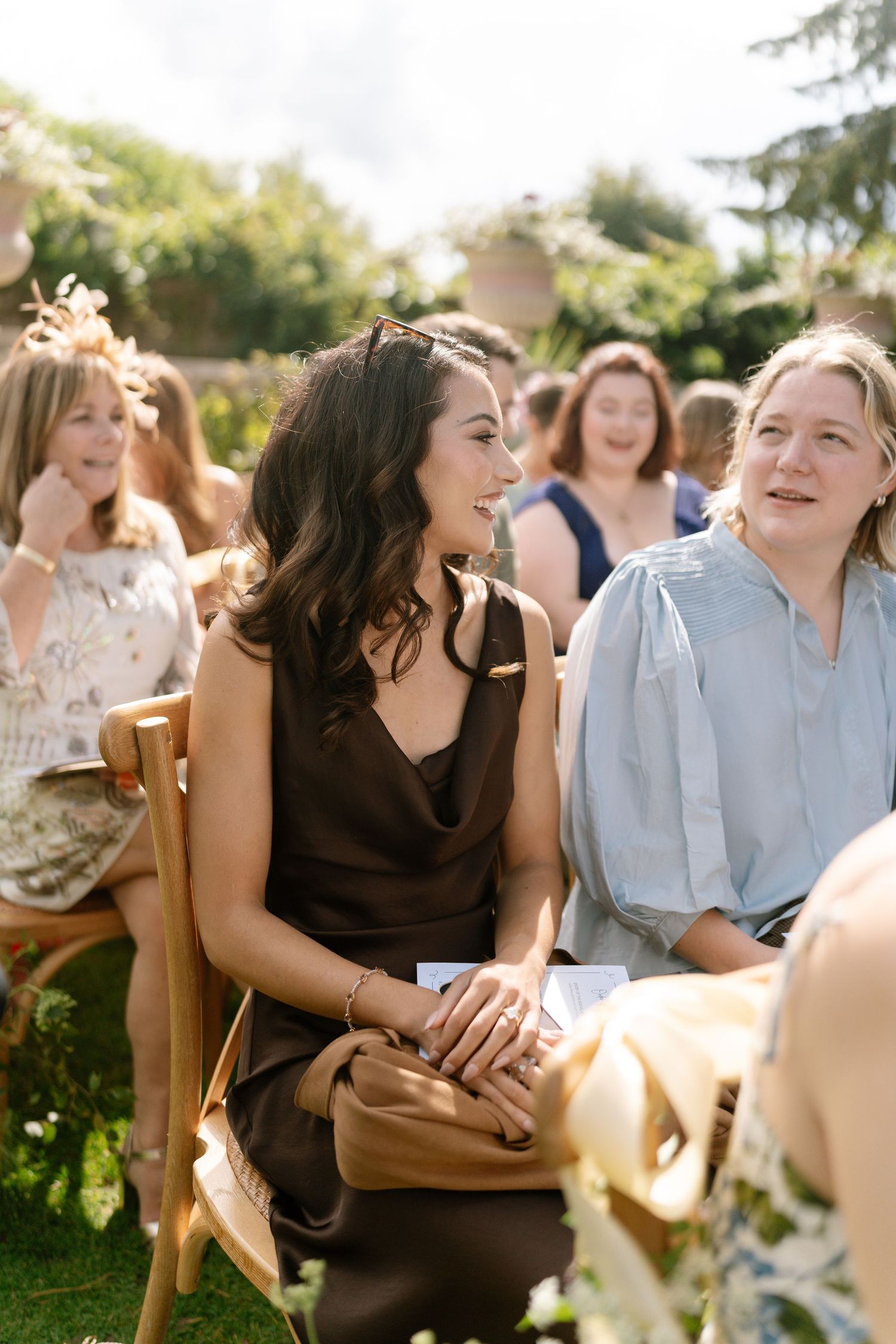 Wedding guests sharing laughs during an outdoor garden ceremony.