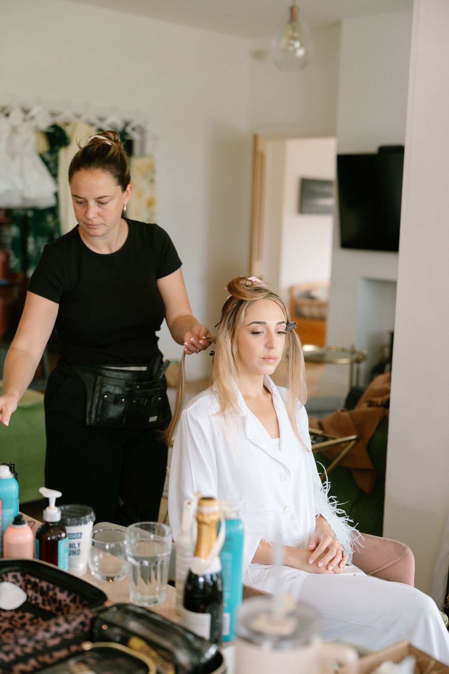 Beauty preparation session with stylist in black working on client in white robe.