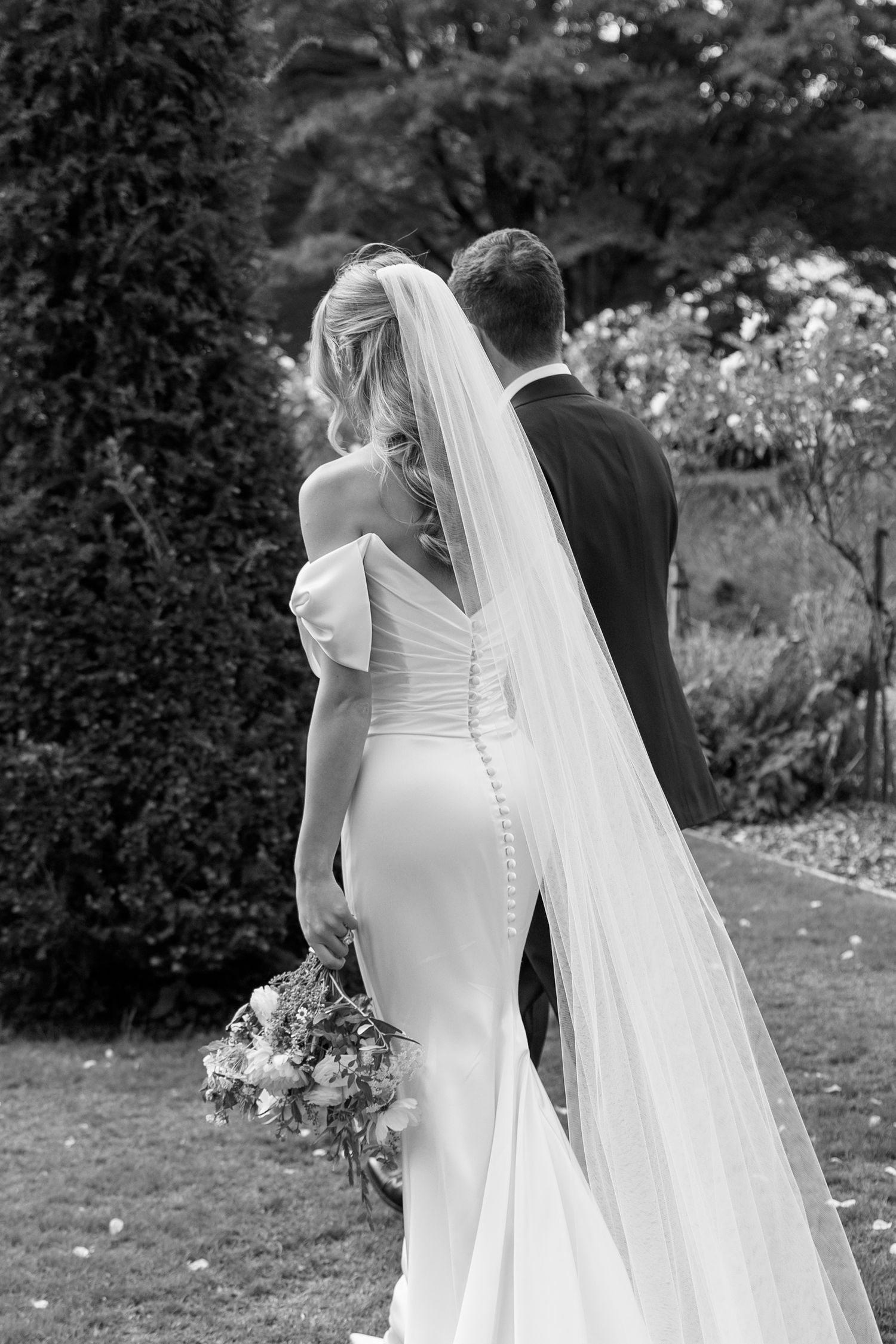 Black and white wedding portrait showcasing a flowing veil and elegant white dress.