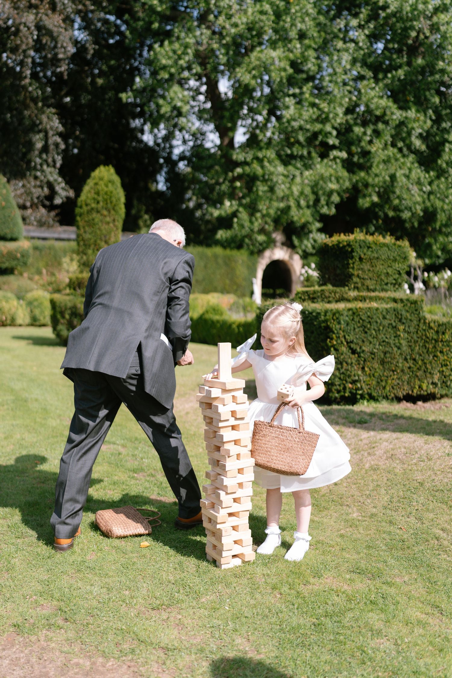 Wedding guests playing giant Jenga on a lawn during reception.