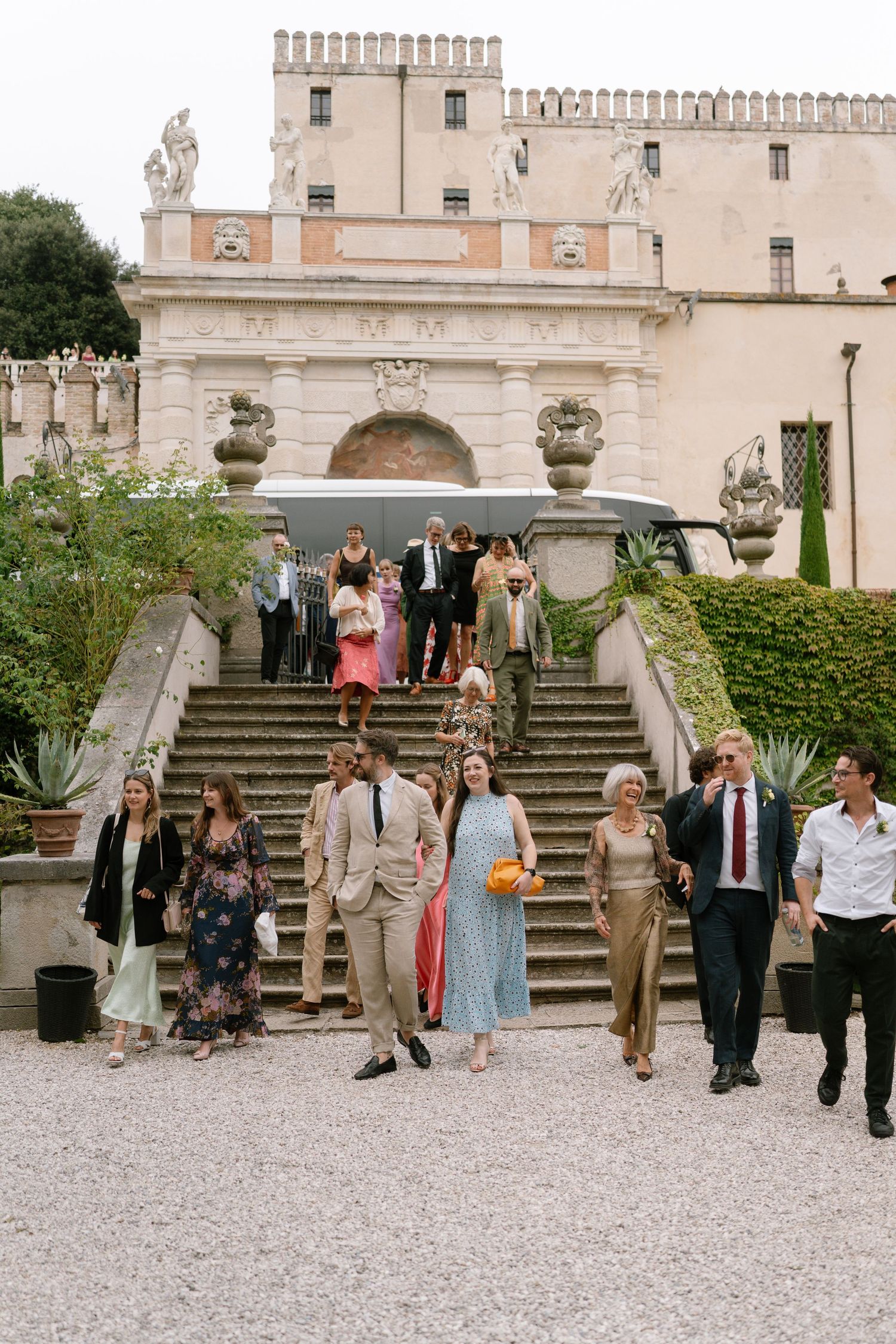 Wedding guests descend grand stone steps at historic venue.