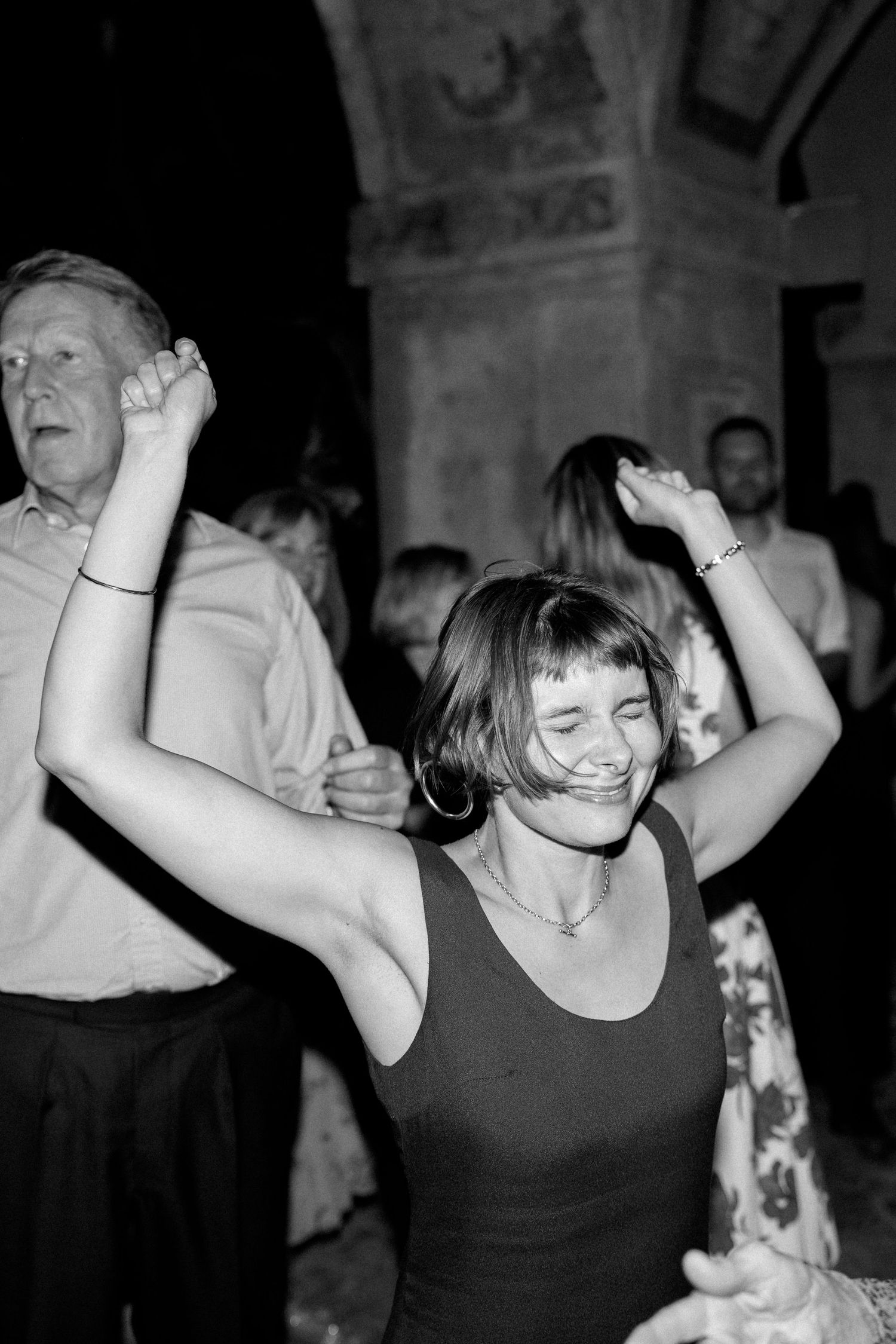 Woman in black tank top dancing energetically at a nightclub.