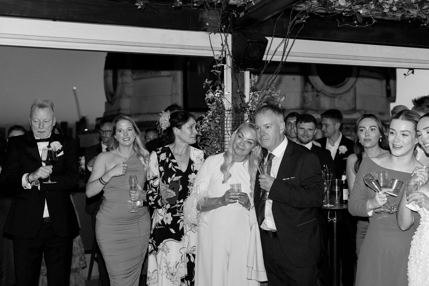 Guests raise their glasses in celebration during an elegant black and white wedding reception.