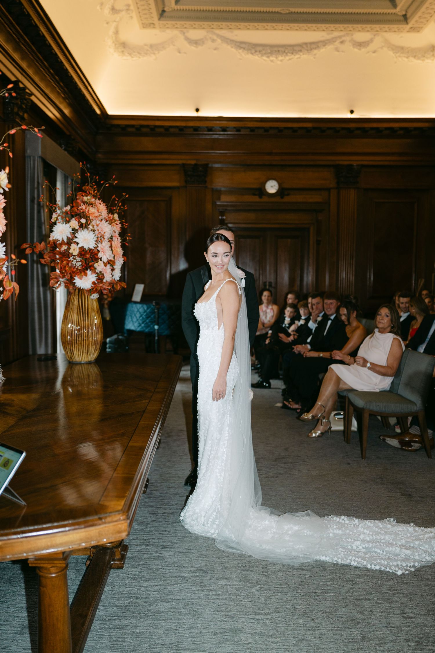 Elegant wedding ceremony setup in a grand room with wood paneling and floral arrangements.