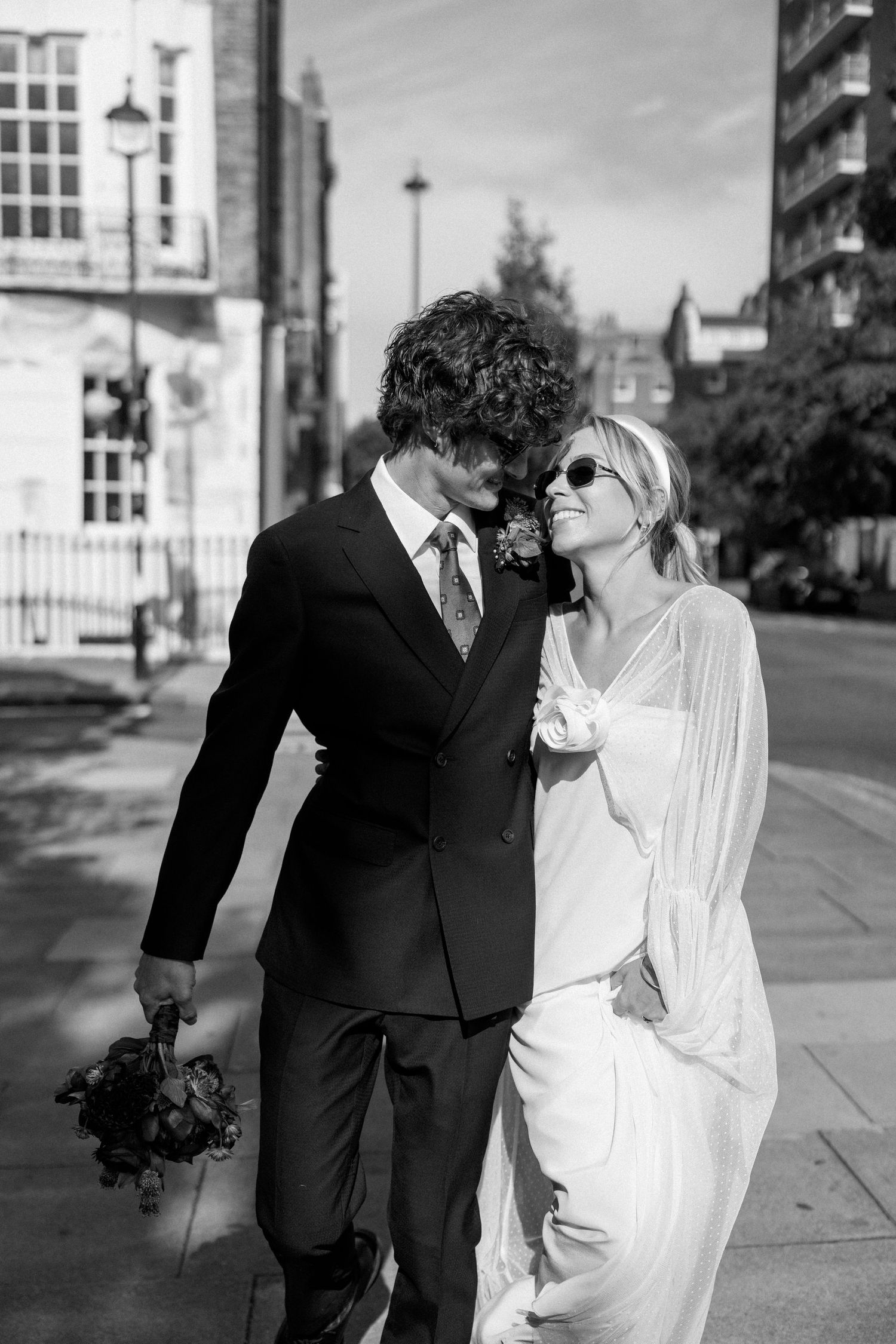 Artistic black and white wedding photos showing romantic moments on a city sidewalk.