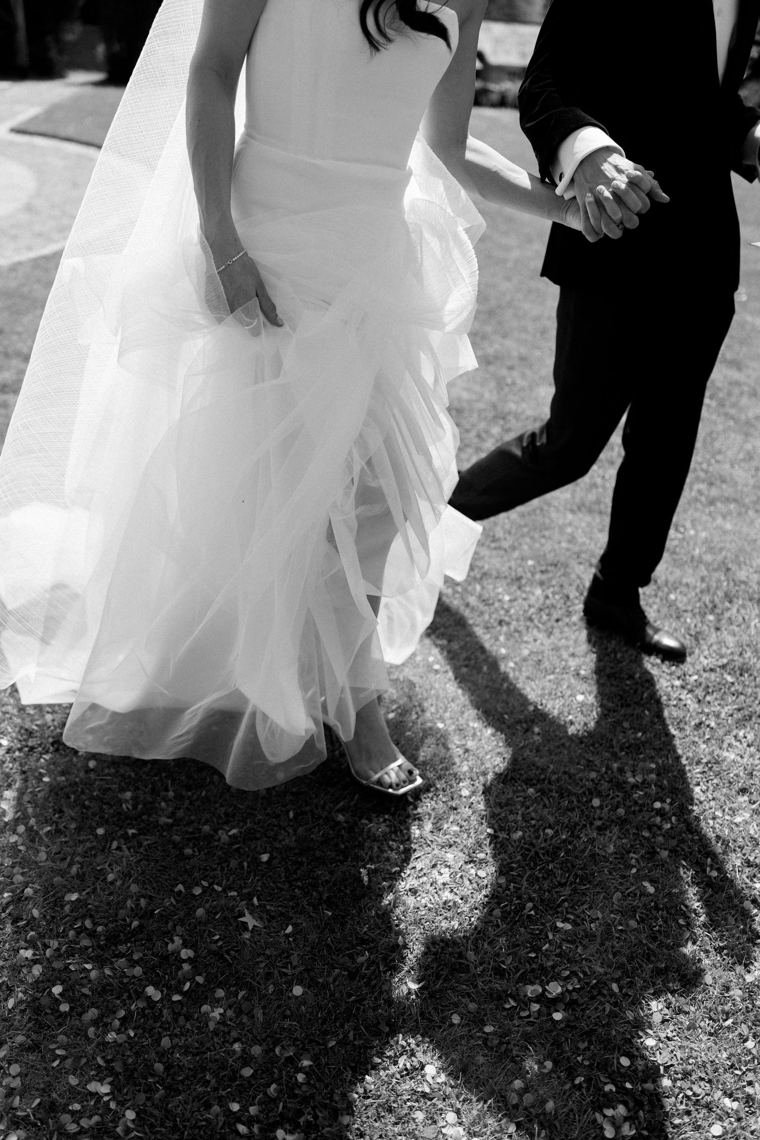 Black and white image of wedding couple's feet dancing among scattered confetti.