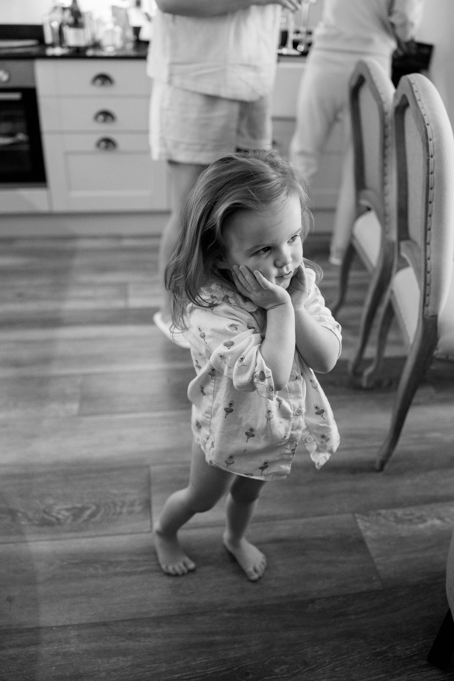 Black and white photo of a small child playing on hardwood floors.