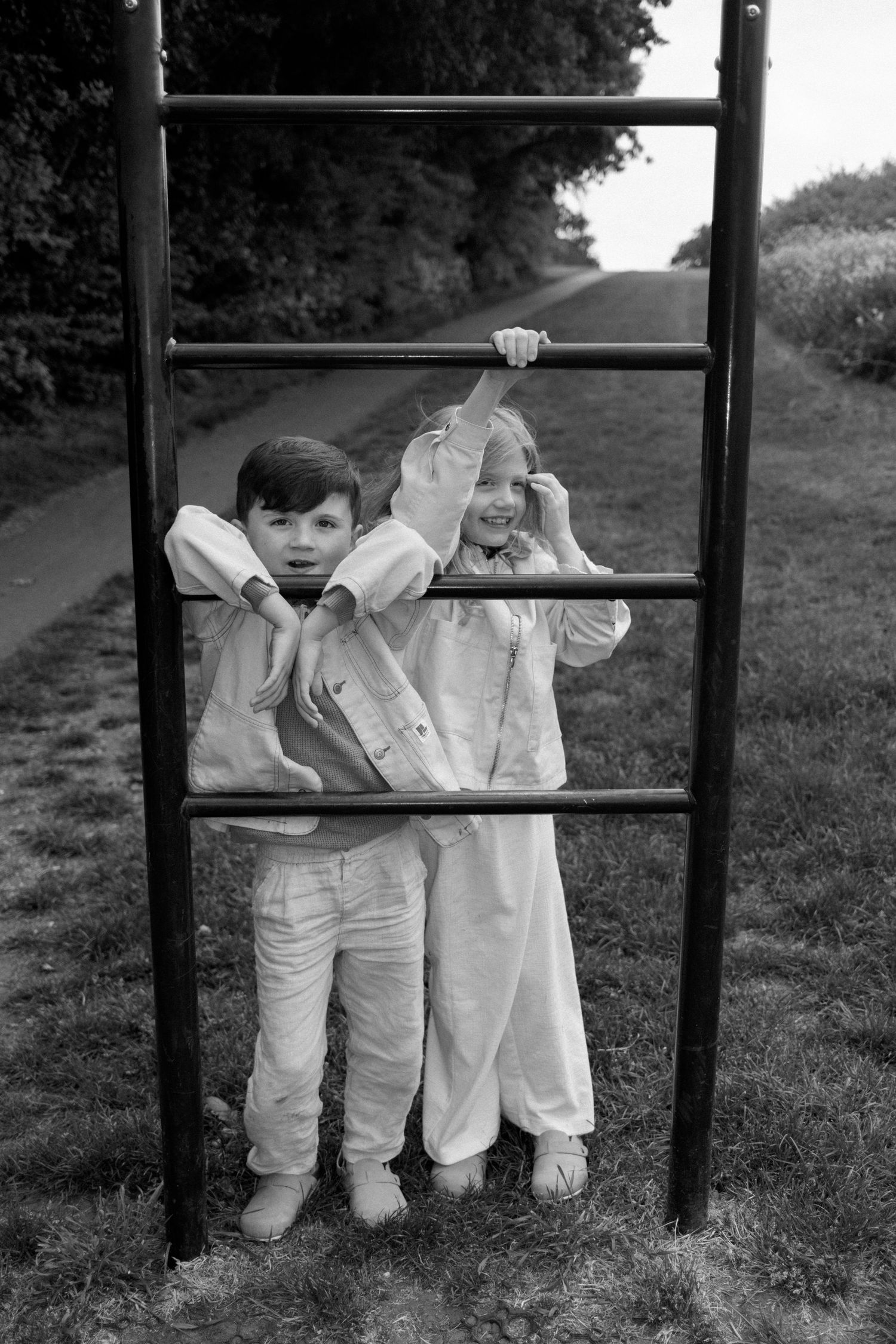 Children in white clothing playing on outdoor playground equipment.
