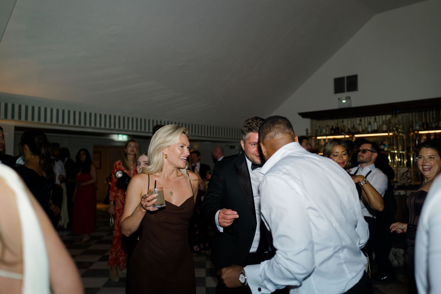 Guests dancing and celebrating at a lively indoor wedding reception party.