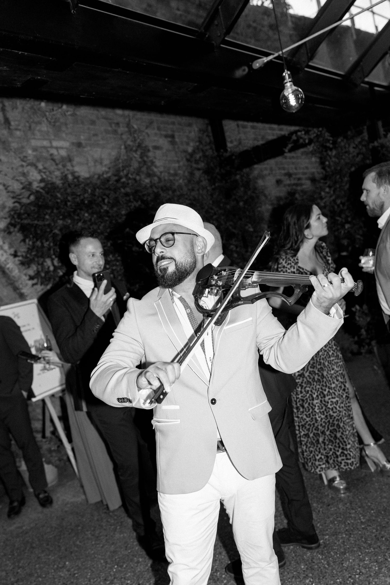 Wedding guests dancing and celebrating in formal attire at an indoor reception.