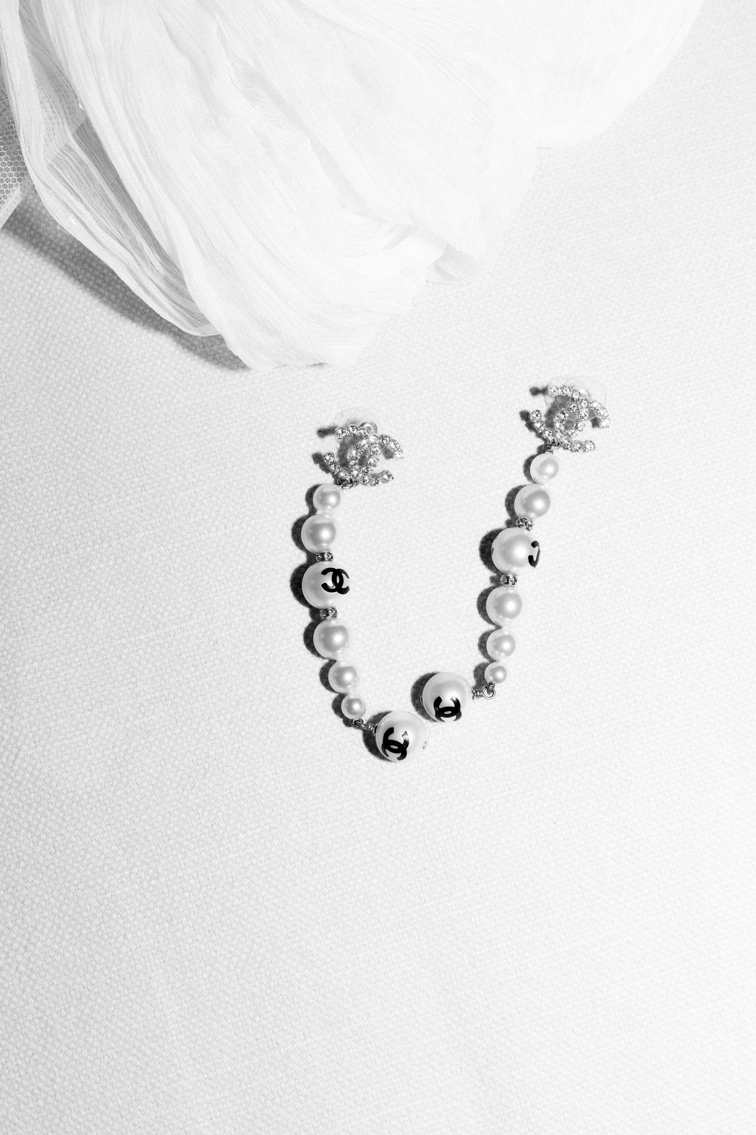 Delicate pearl jewelry arrangement on white fabric background.