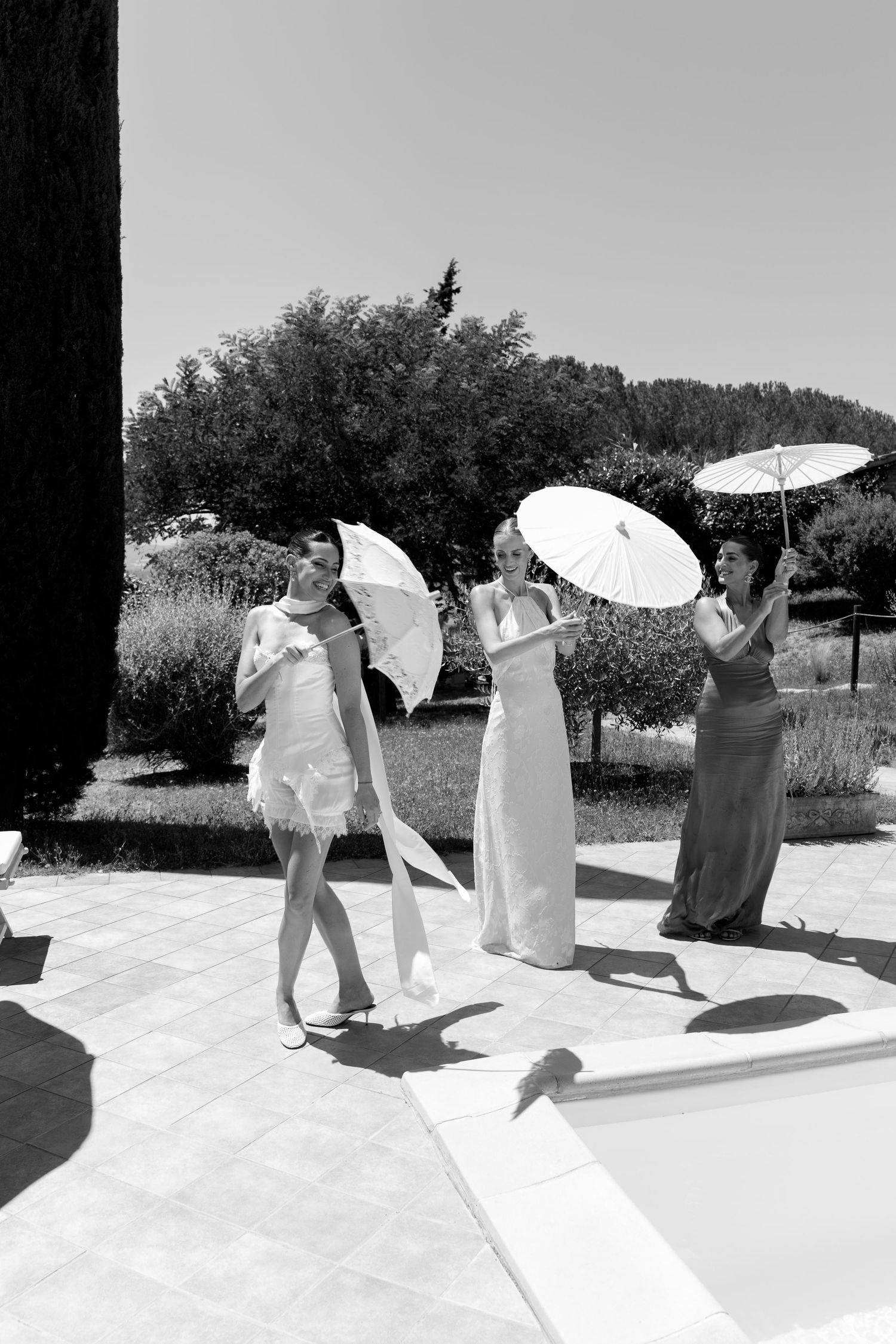 A series of black and white photos showing people with white parasols dancing in sunlight.