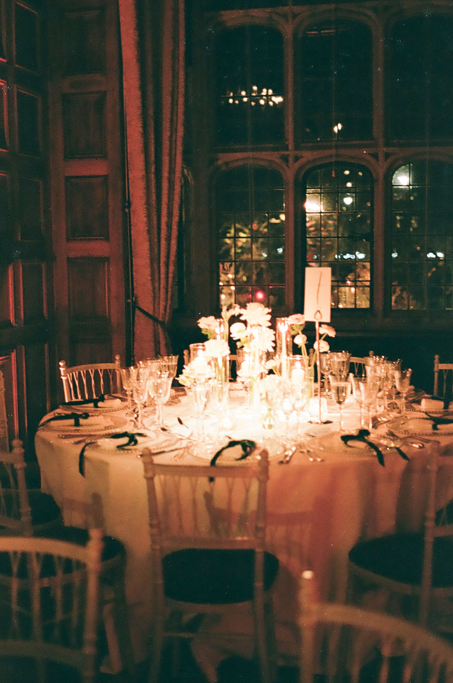 Romantic candlelit reception tables set for an evening wedding celebration with glowing ambient lighting.
