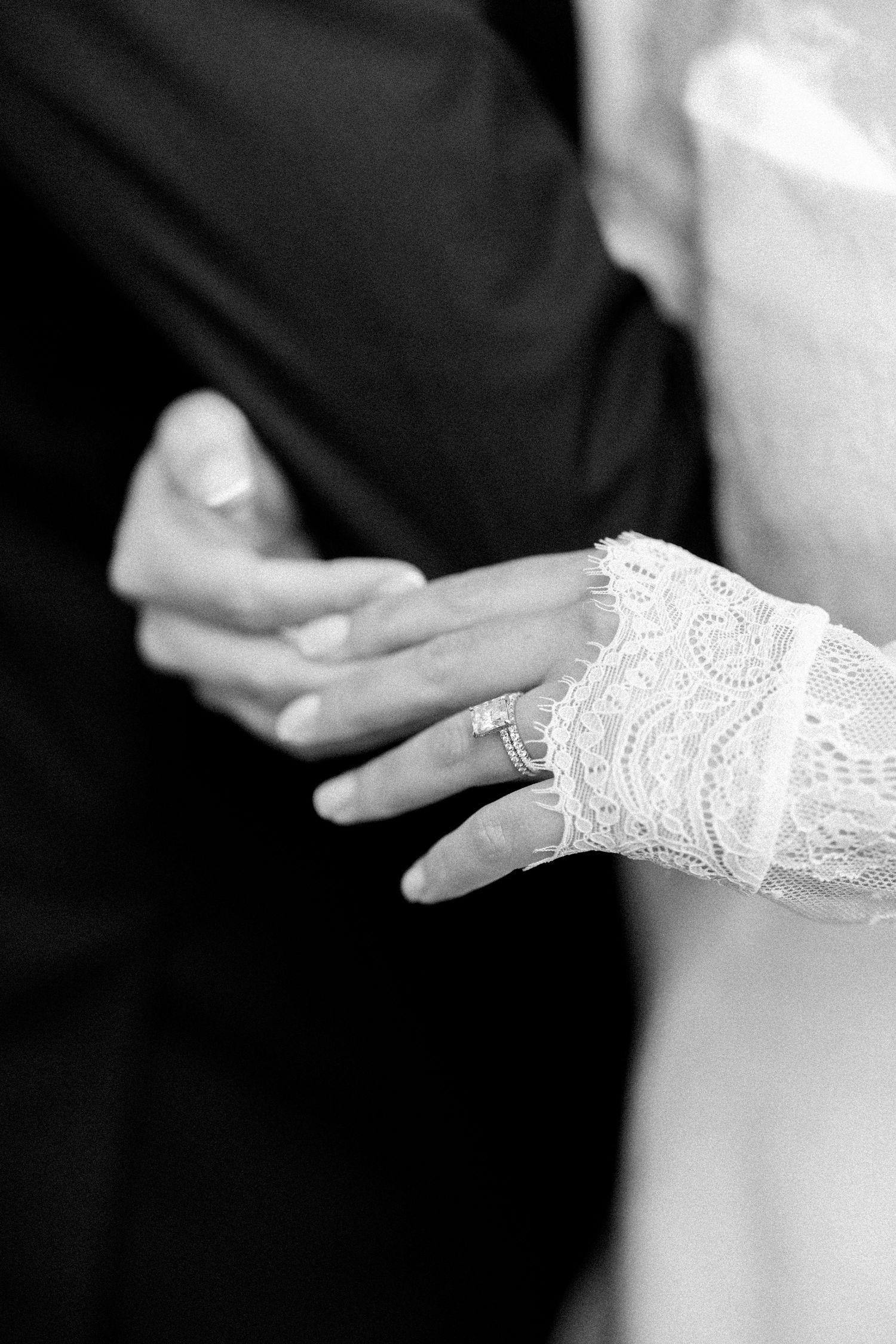 Close-up detail of delicate lace on bride's sleeve in black and white.