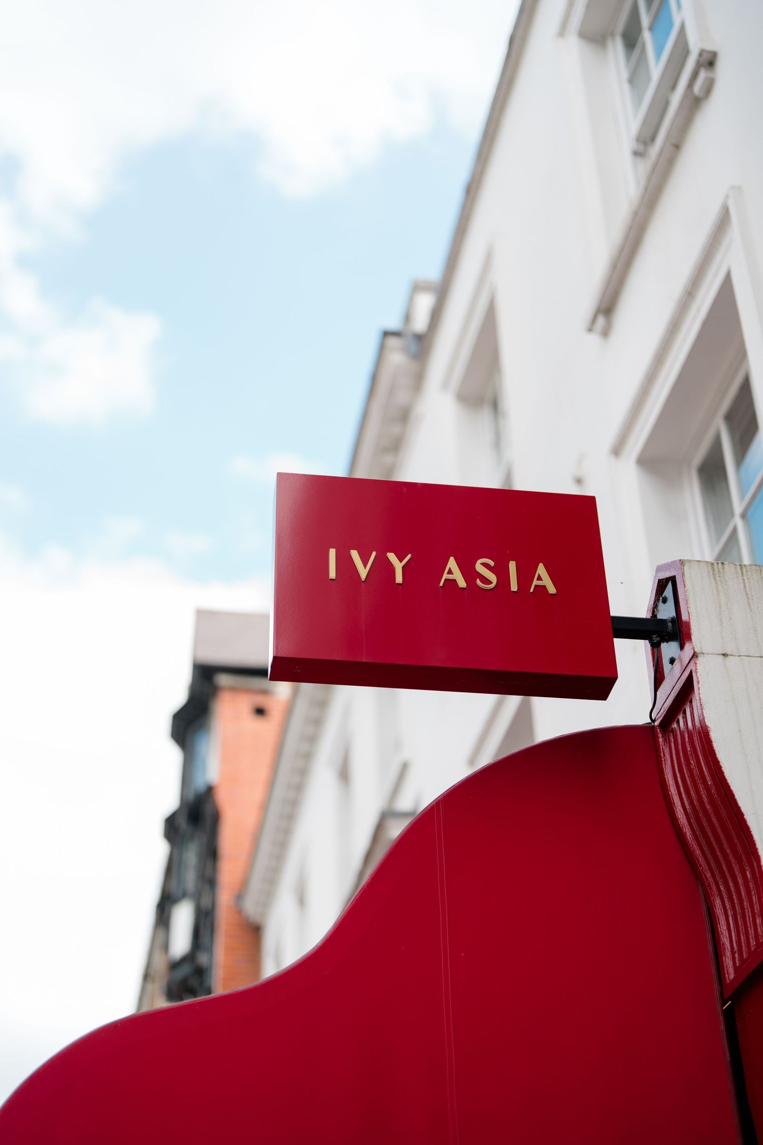 Red awning with gold lettering on a white building exterior.