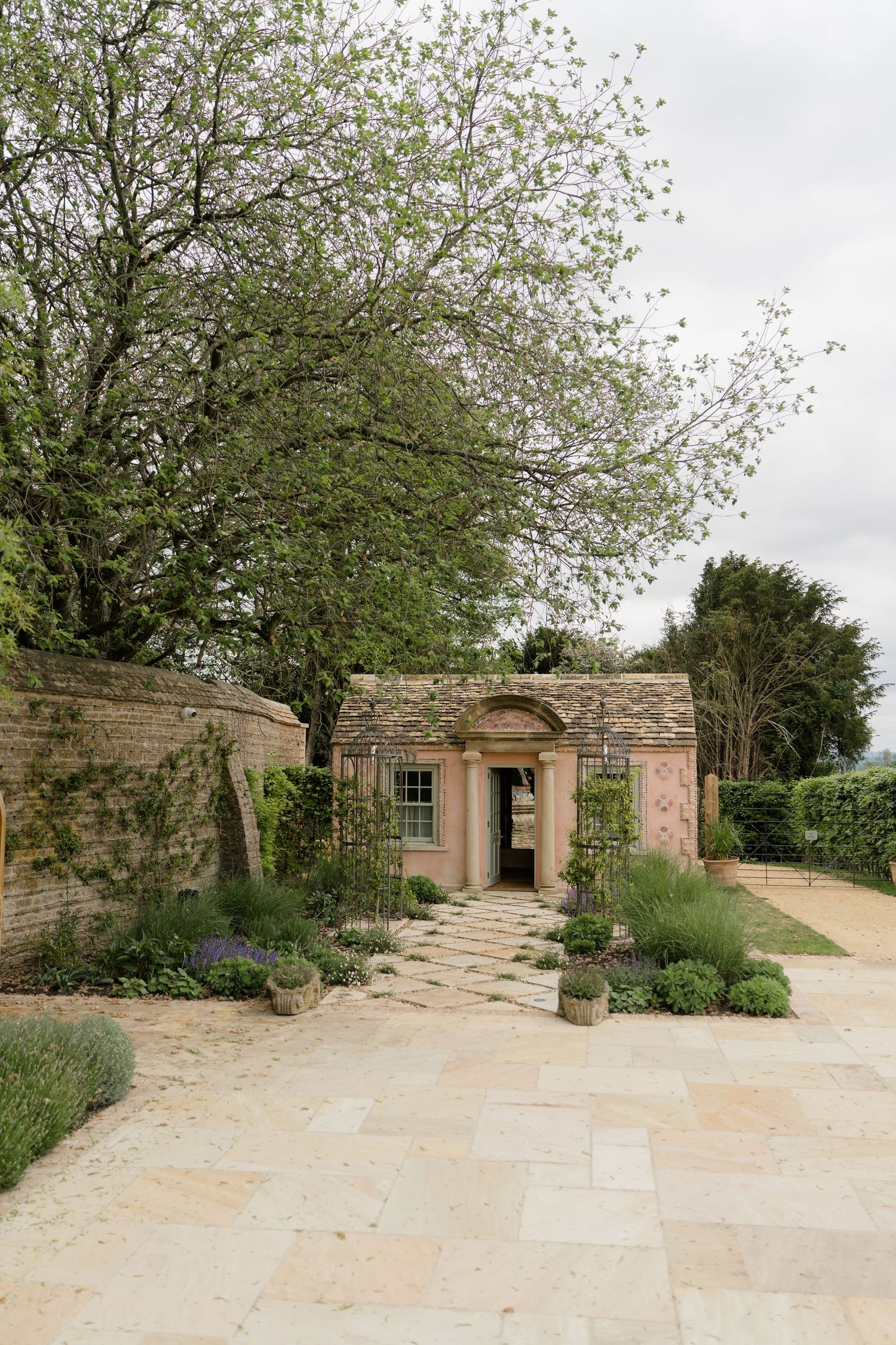 Stone garden folly with arched doorway surrounded by lavender and climbing plants at a wedding venue.