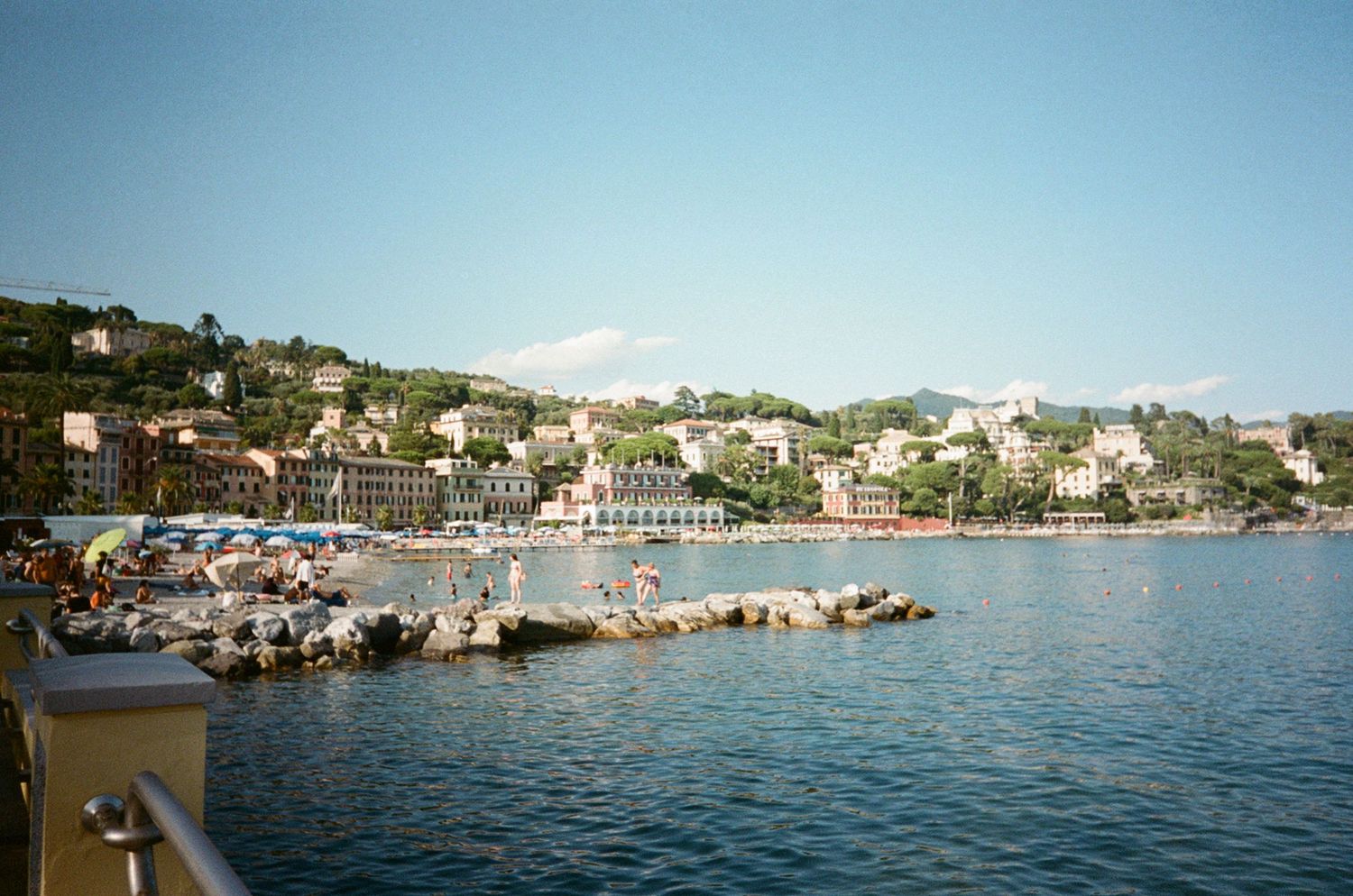 Scenic Italian Riviera coastal town with colorful buildings, sandy beach, and calm blue Mediterranean sea.