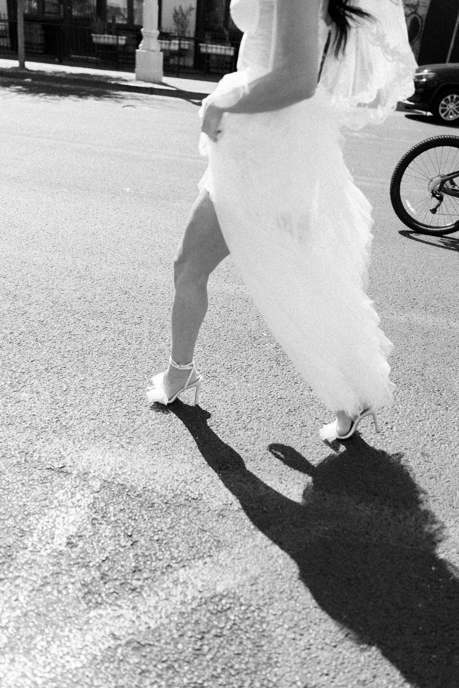 Shadows and movement of a bride's dress captured on pavement in black and white.