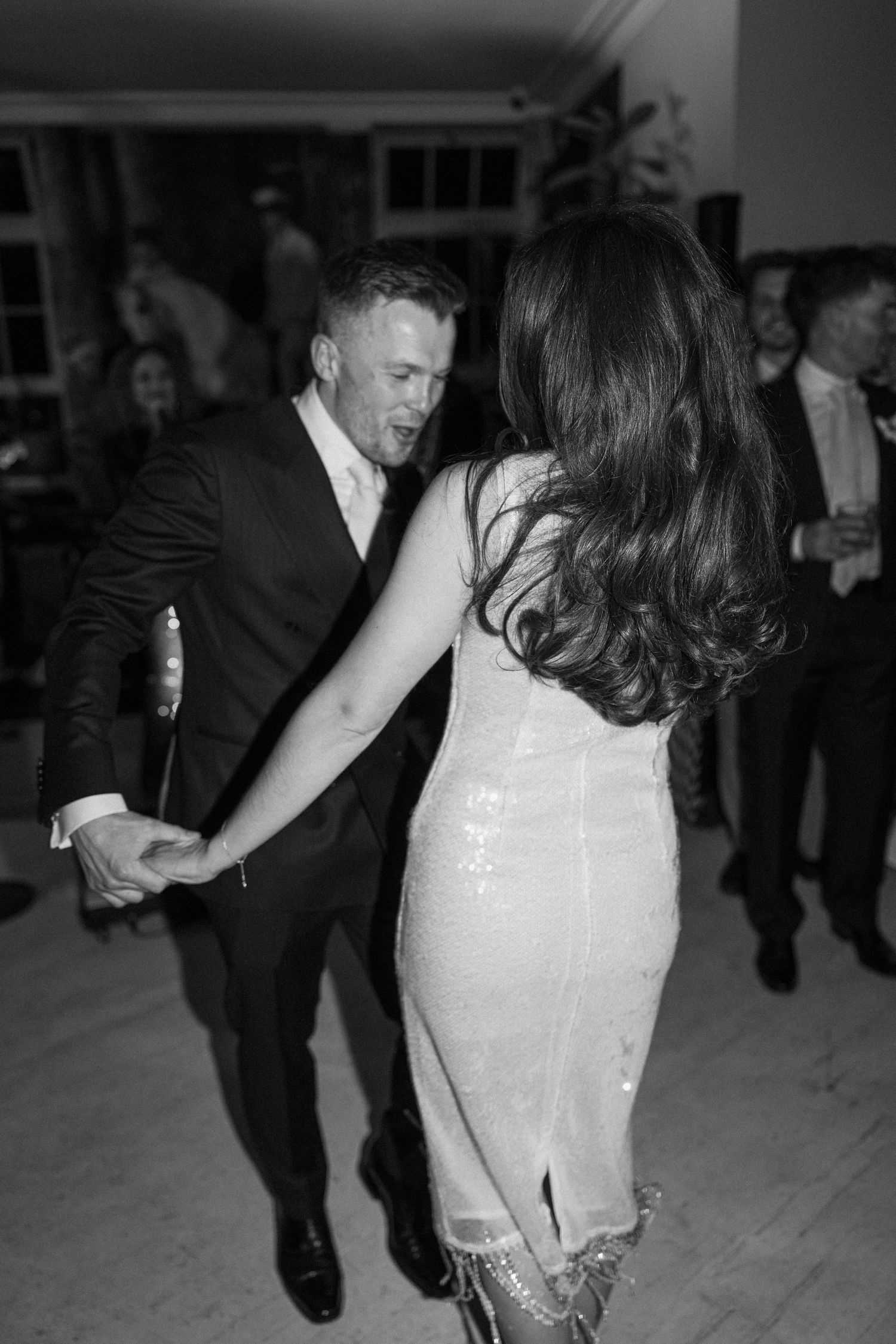 Bride and groom sharing energetic dance together at evening wedding reception in black and white.