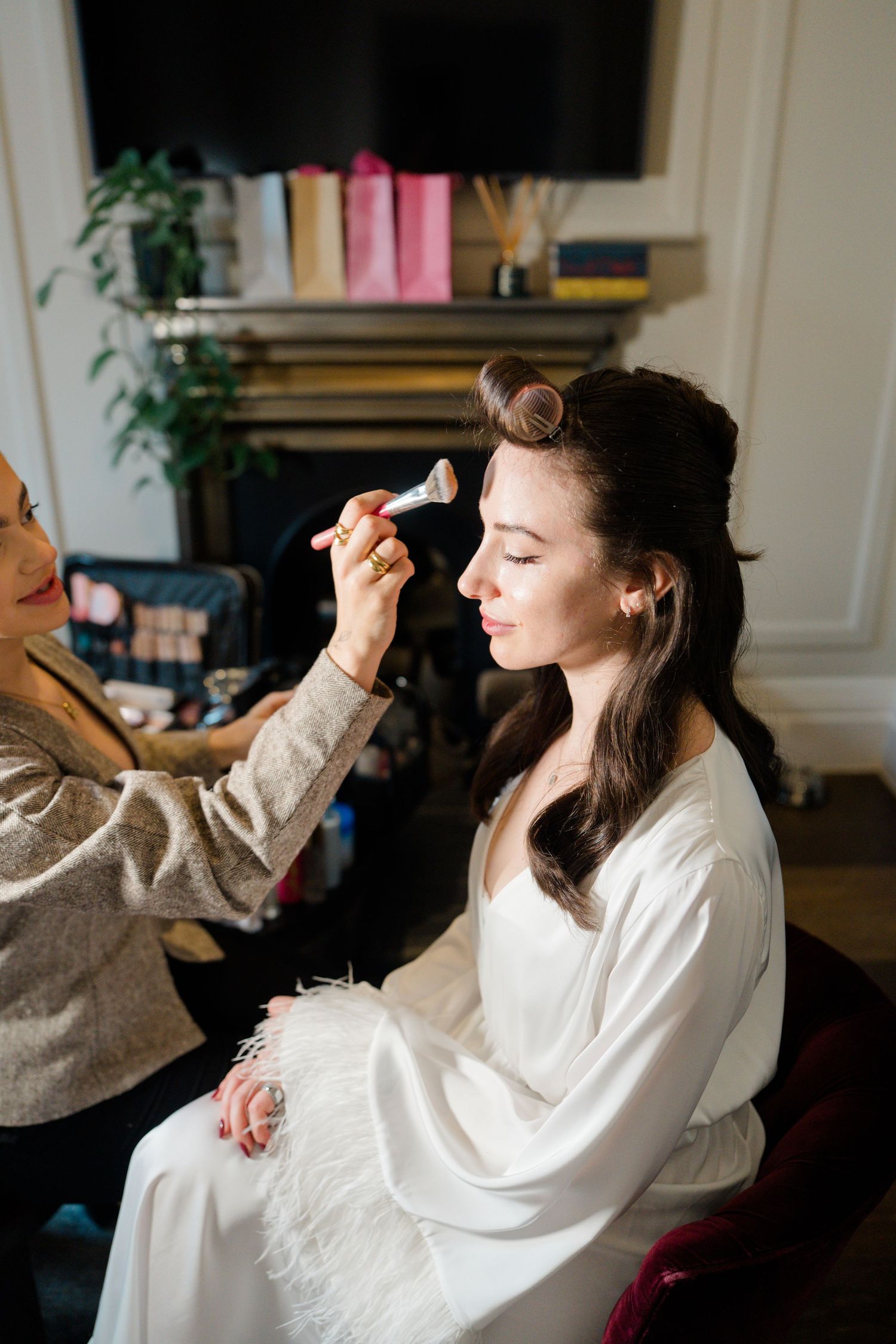 Makeup artist applying powder to bride's face with brush during bridal preparations.