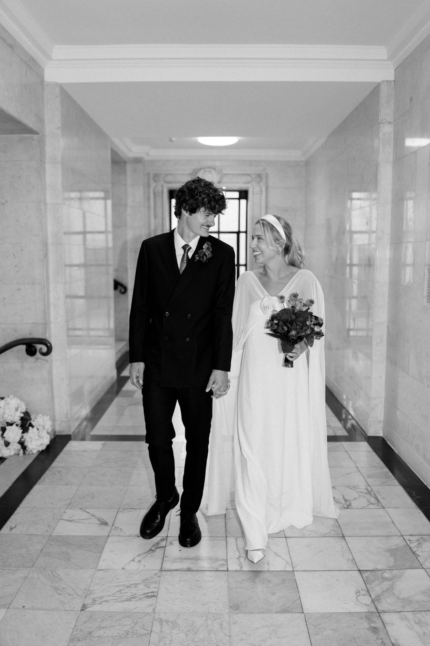 Wedding couple walking down a bright marble hallway in a series of artistic photos.