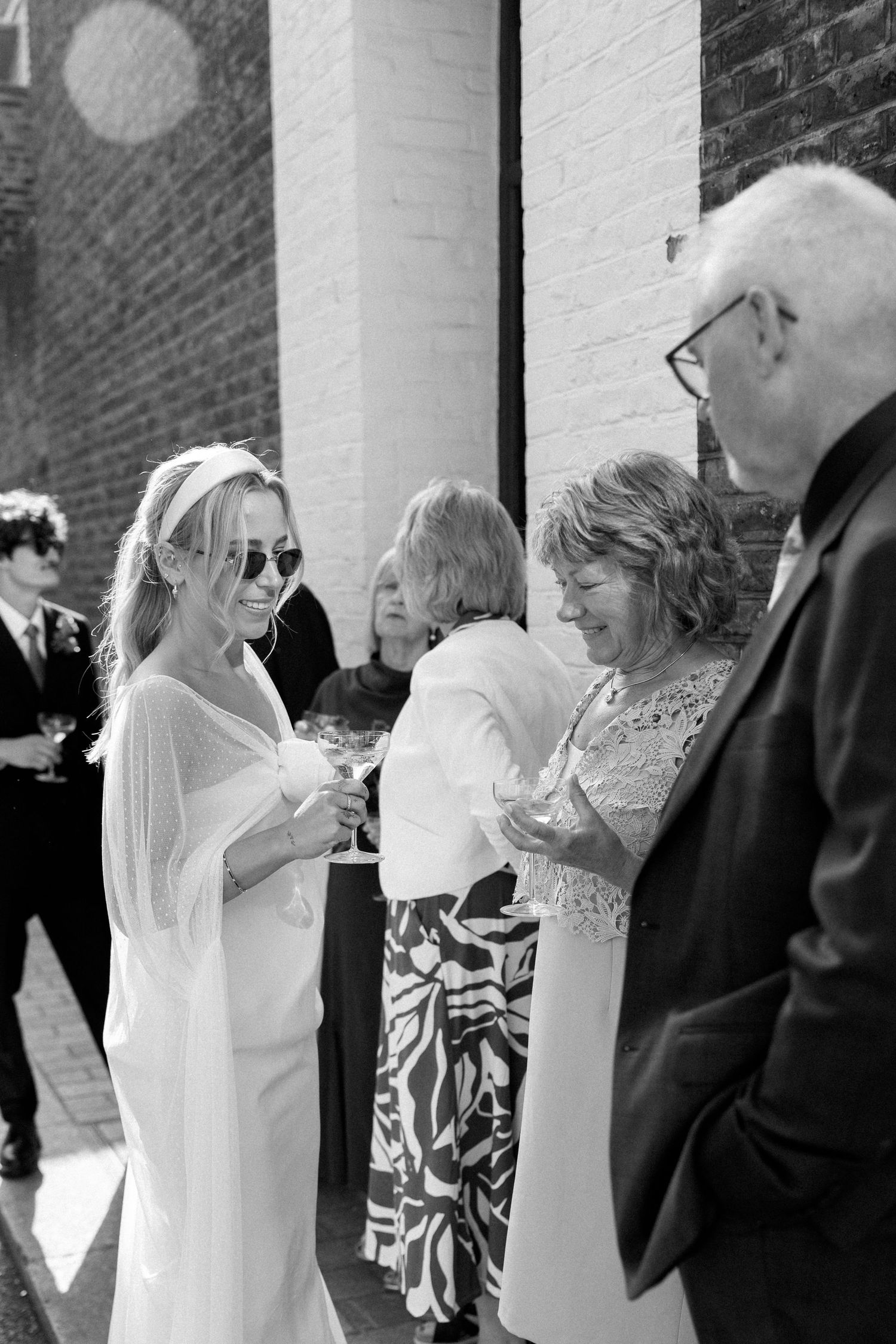 Wedding guests mingling and chatting outside a columned building entrance.
