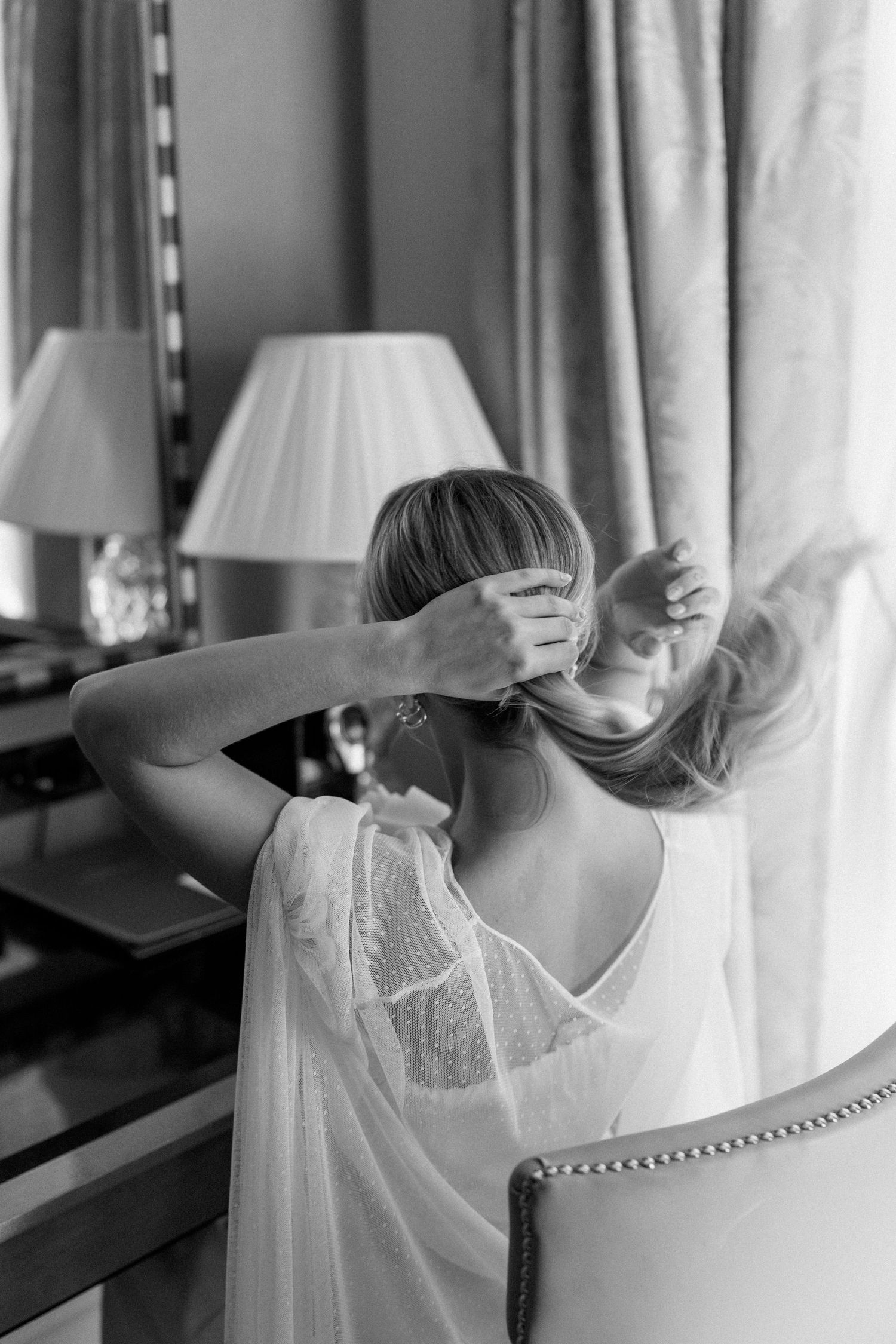 Intimate getting ready moment captured in black and white at vanity mirror.