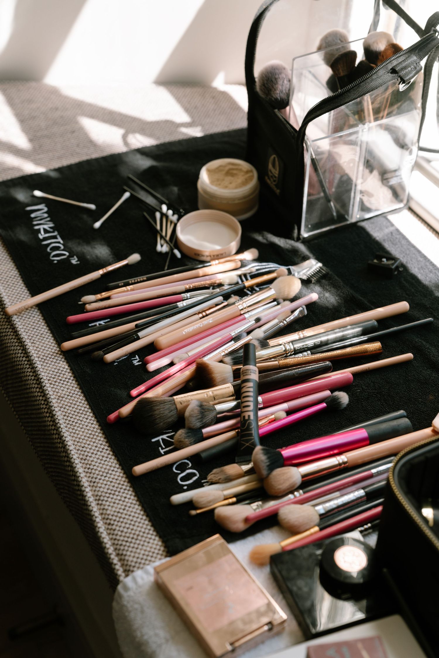 Collection of makeup brushes and beauty tools scattered on a dark surface.