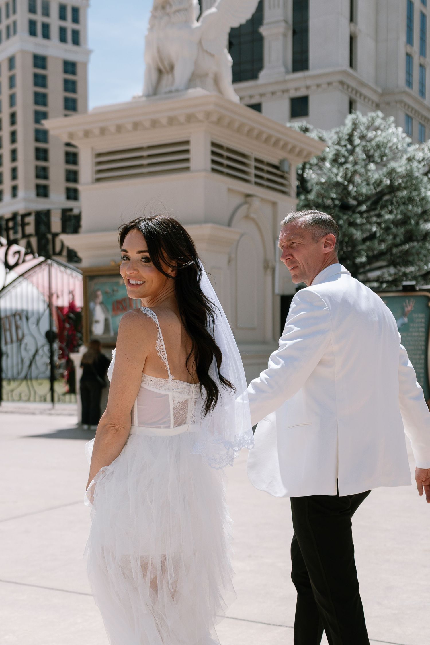 A couple in formal wedding attire walking through a luxurious hotel hallway in Las Vegas.