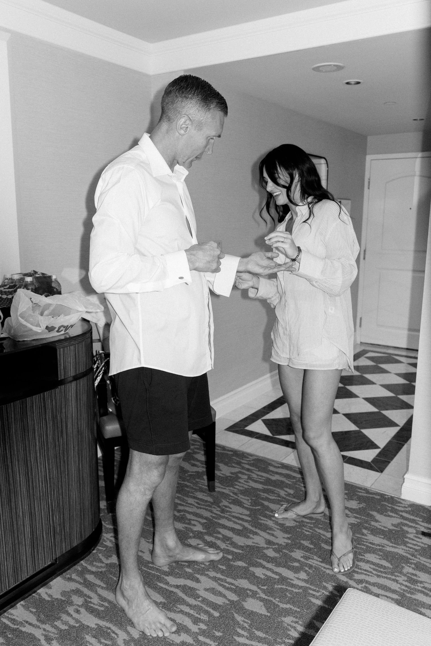 People getting ready in a room with checkerboard floor pattern.