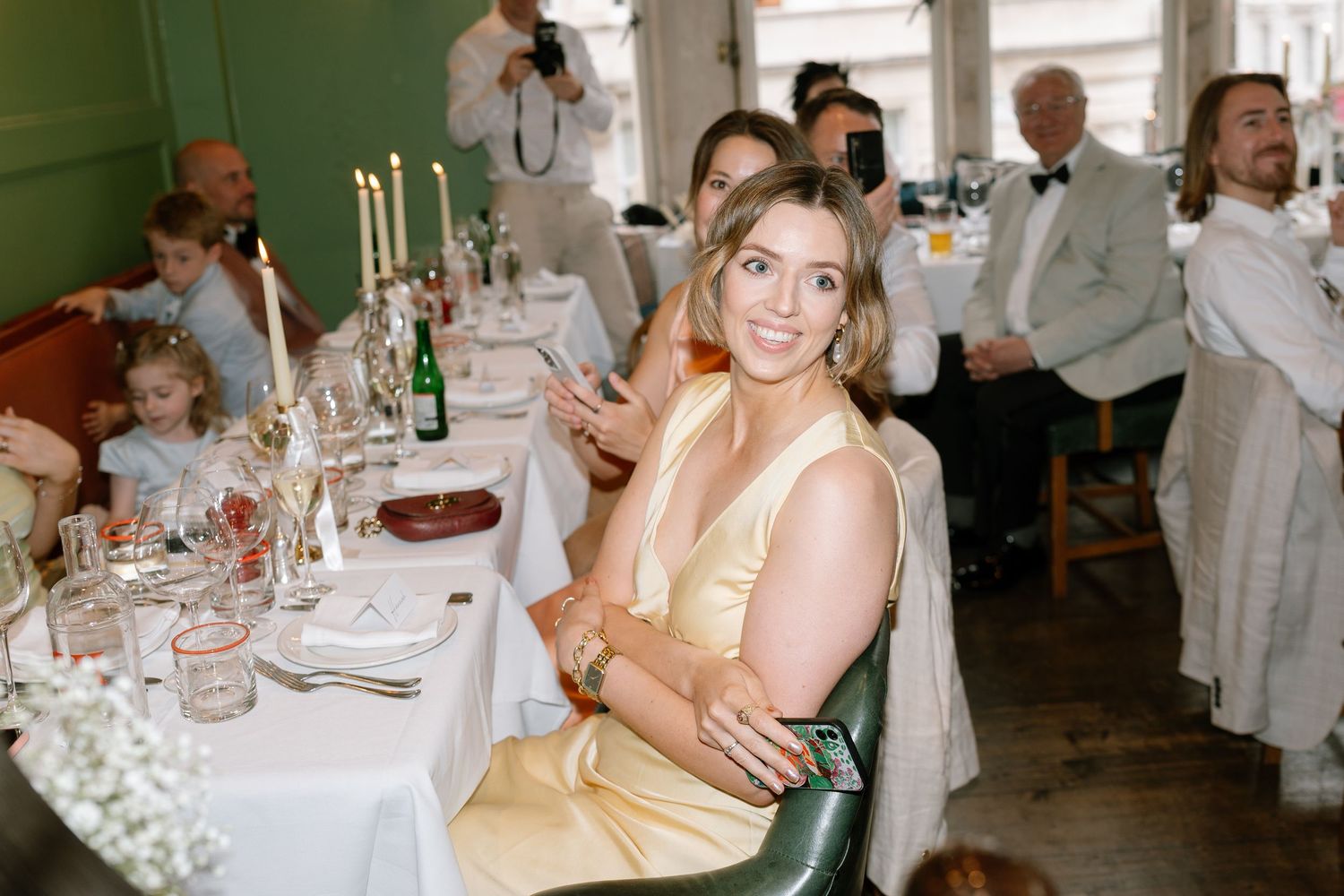 Guest seated at an elegant wedding reception table with candles and formal place settings.