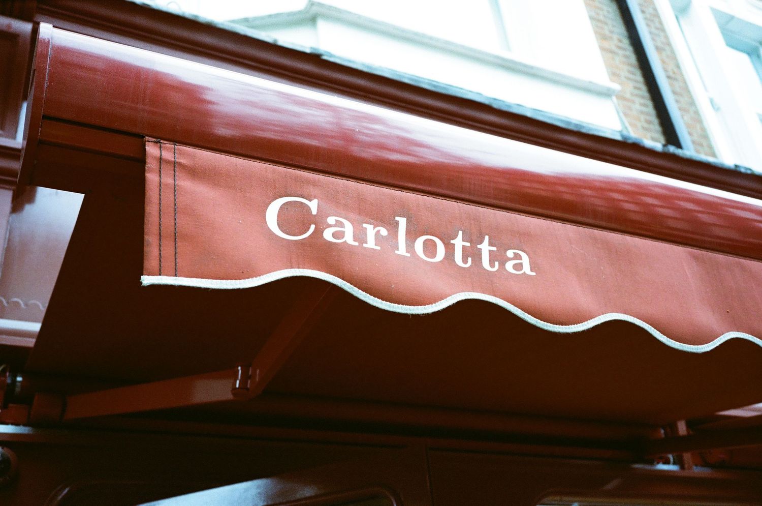 Red and white striped awning extends over a storefront with the name Carlotta visible on the signage.