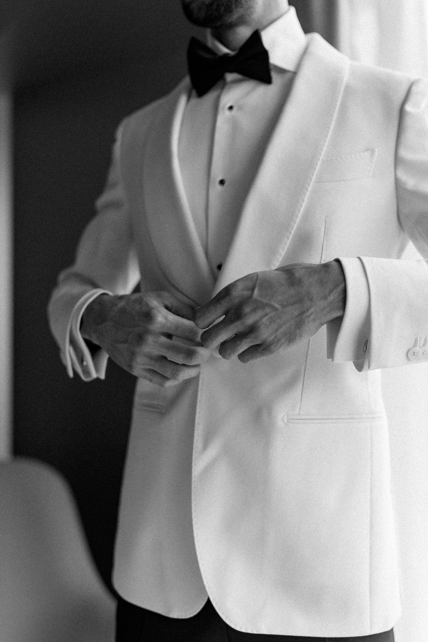 Series of photos showing details of a white tuxedo jacket being buttoned.