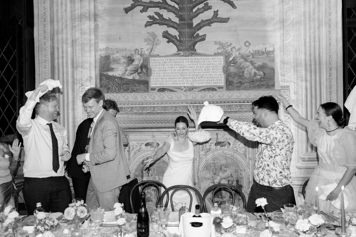 Black and white photo of guests celebrating at an elegant reception with ornate wall decorations.