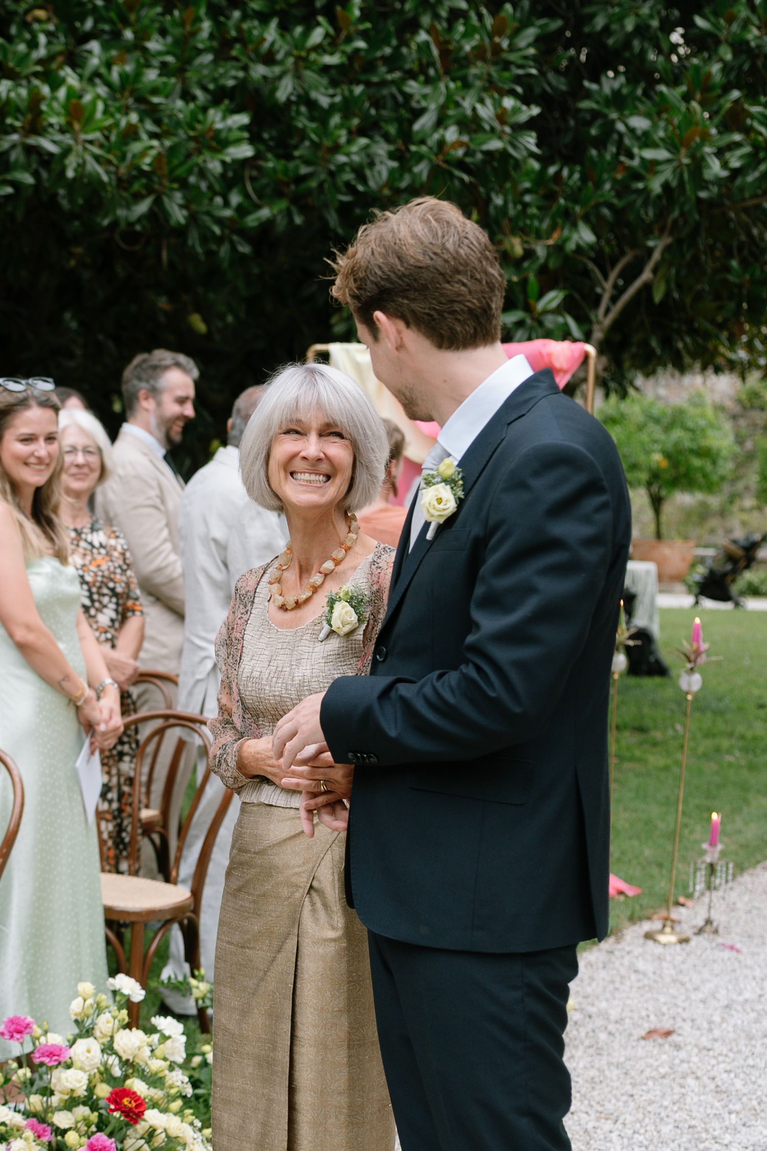 Wedding guests mingling on a gravel path surrounded by greenery.